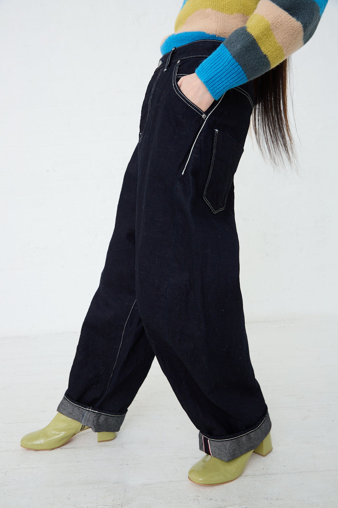 A woman wearing a Mina Perhonen Always Balloon Wide Pant in Indigo. Side view.  Model's hands are in front pockets.