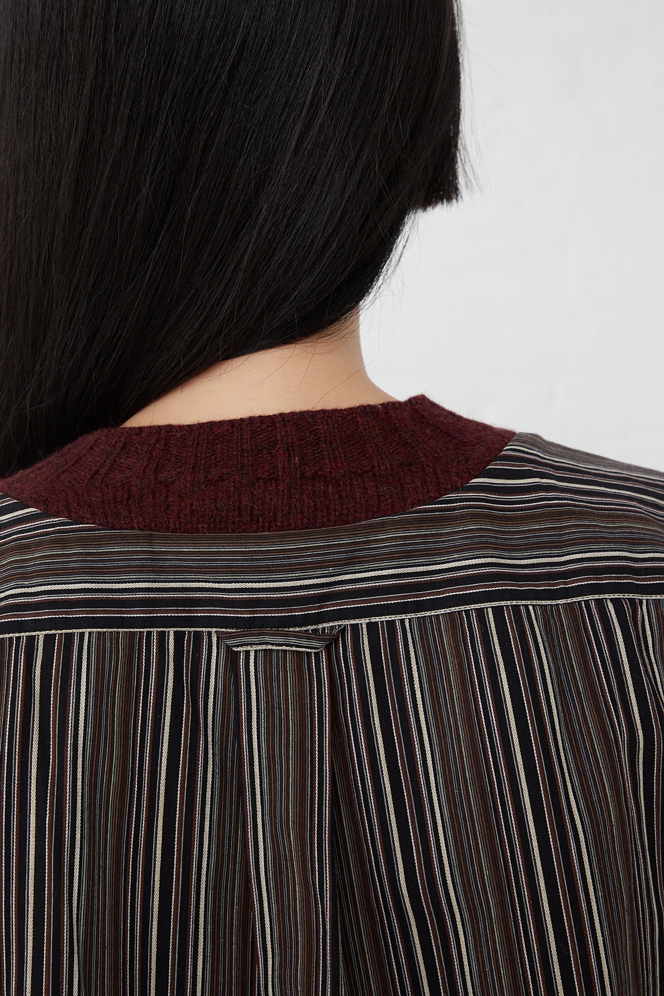 The woman is wearing the Bless No. 68 Front Insert Pullover in Stripe, a long sleeve pullover made of a wool and cotton blend fabric, with stripes on the back.