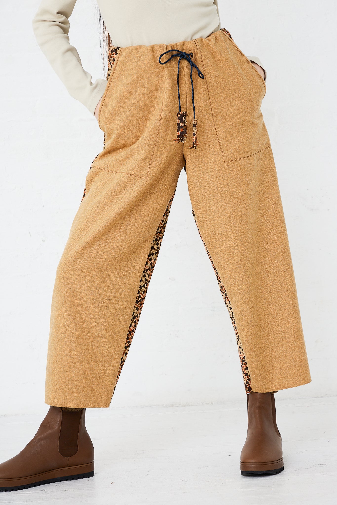 A woman is standing in a room wearing the Thank You Have A Good Day Wool Contrast Project Suit in Mustard. Pants up close.