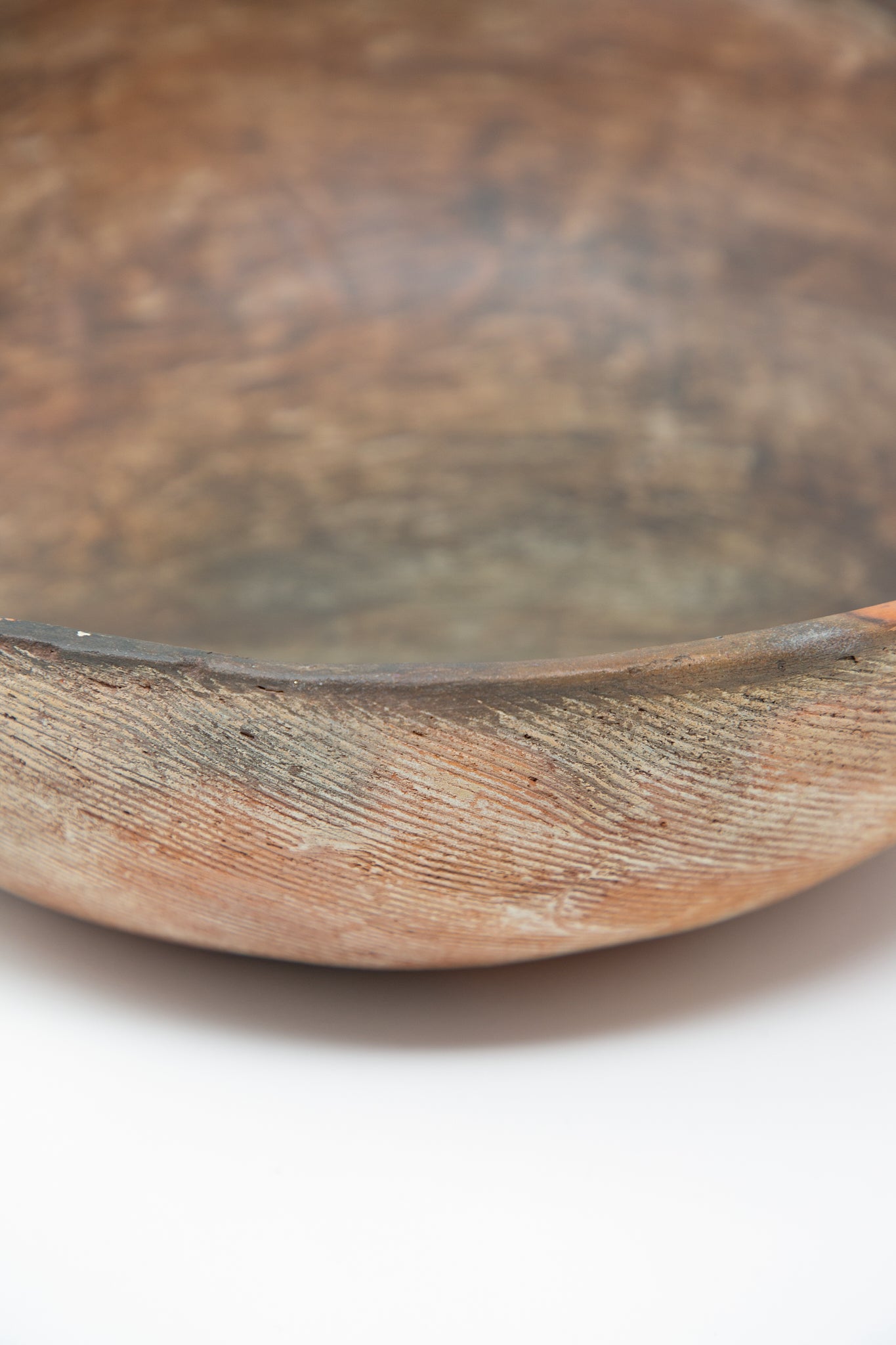 A Plaza Bolivar Julia Bowl of Illusions in Red Clay on a white surface. Up close view of clay texture.