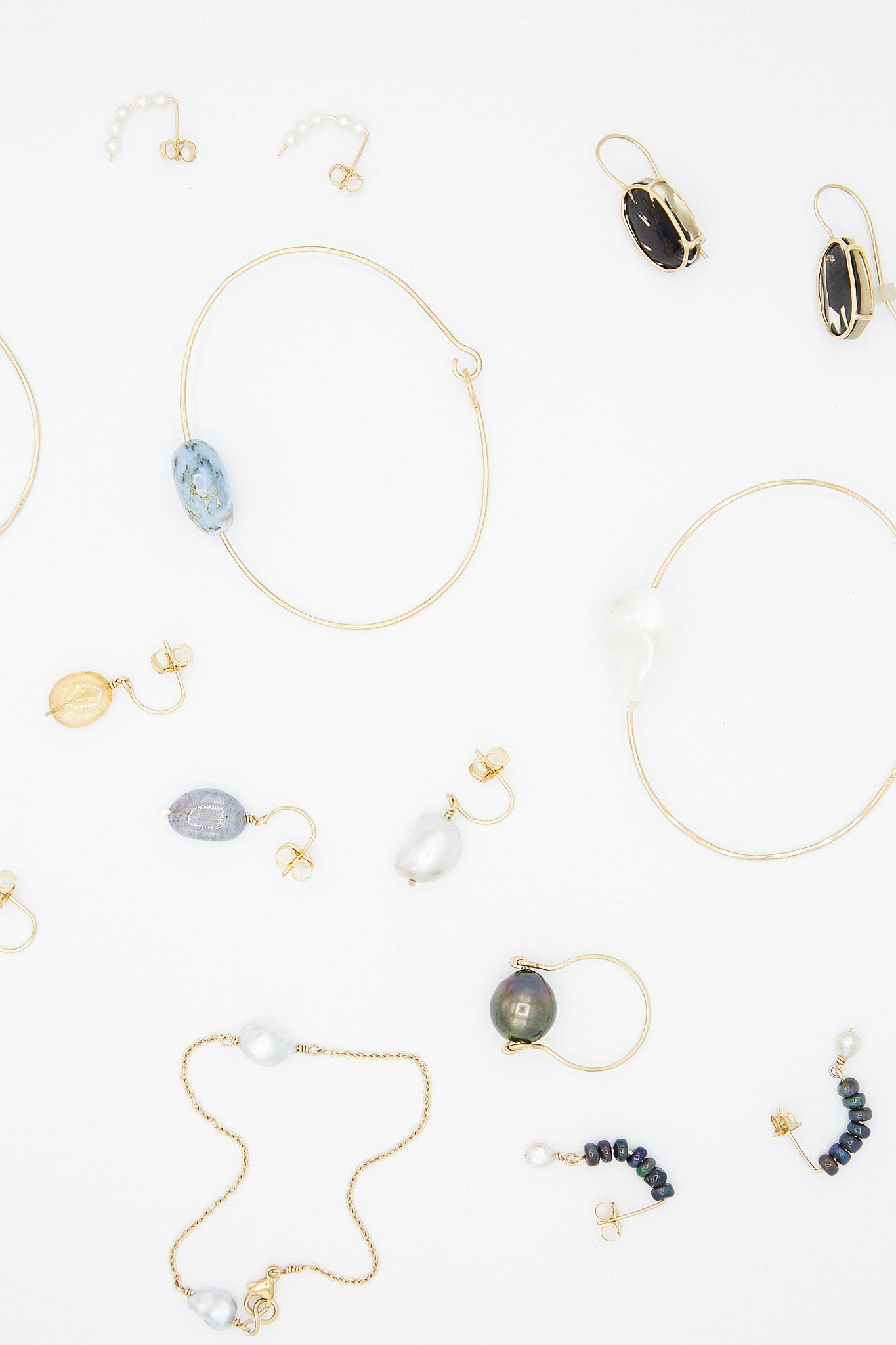 A collection of Mary MacGill Handmade necklaces, 14K Floating Drop Earrings in Cowrie Shell, and bracelets featuring Cowrie Shell and 14K Gold accents.