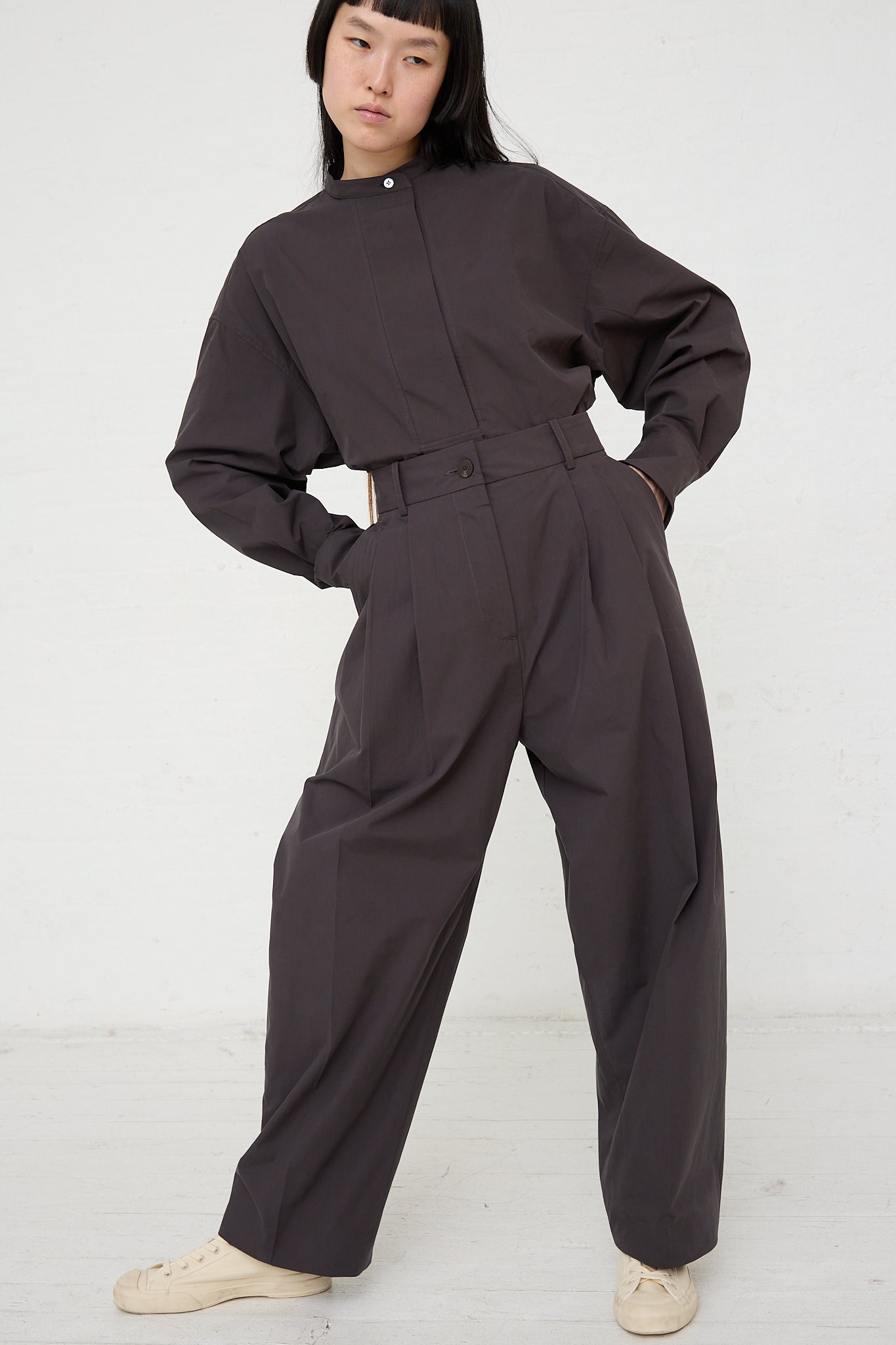 The model is wearing a Studio Nicholson Acuna Double Pleat Front Trouser in Asphalt. Front view and full length. Model's hands are in pockets.