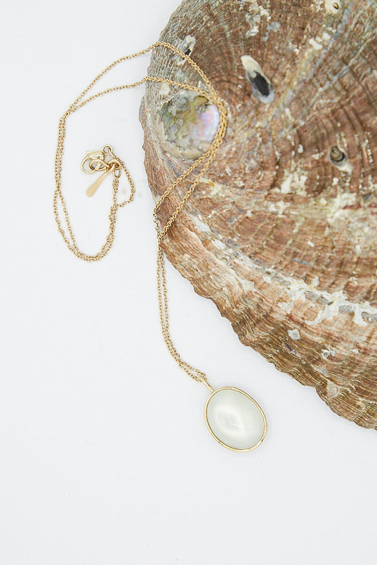 A Mary MacGill 14K Floating Necklace in Ceylon Moonstone featuring a pearl delicately perched atop a shell adorned with Ceylon Moonstone, crafted in exquisite 14K gold.