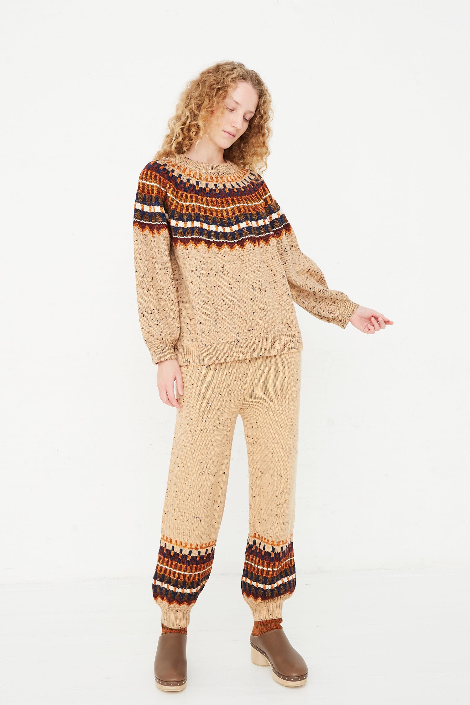 A woman wearing a beige sweater with Misha & Puff Fair Isle Warm-Up Pant in Seed Confetti detailing.