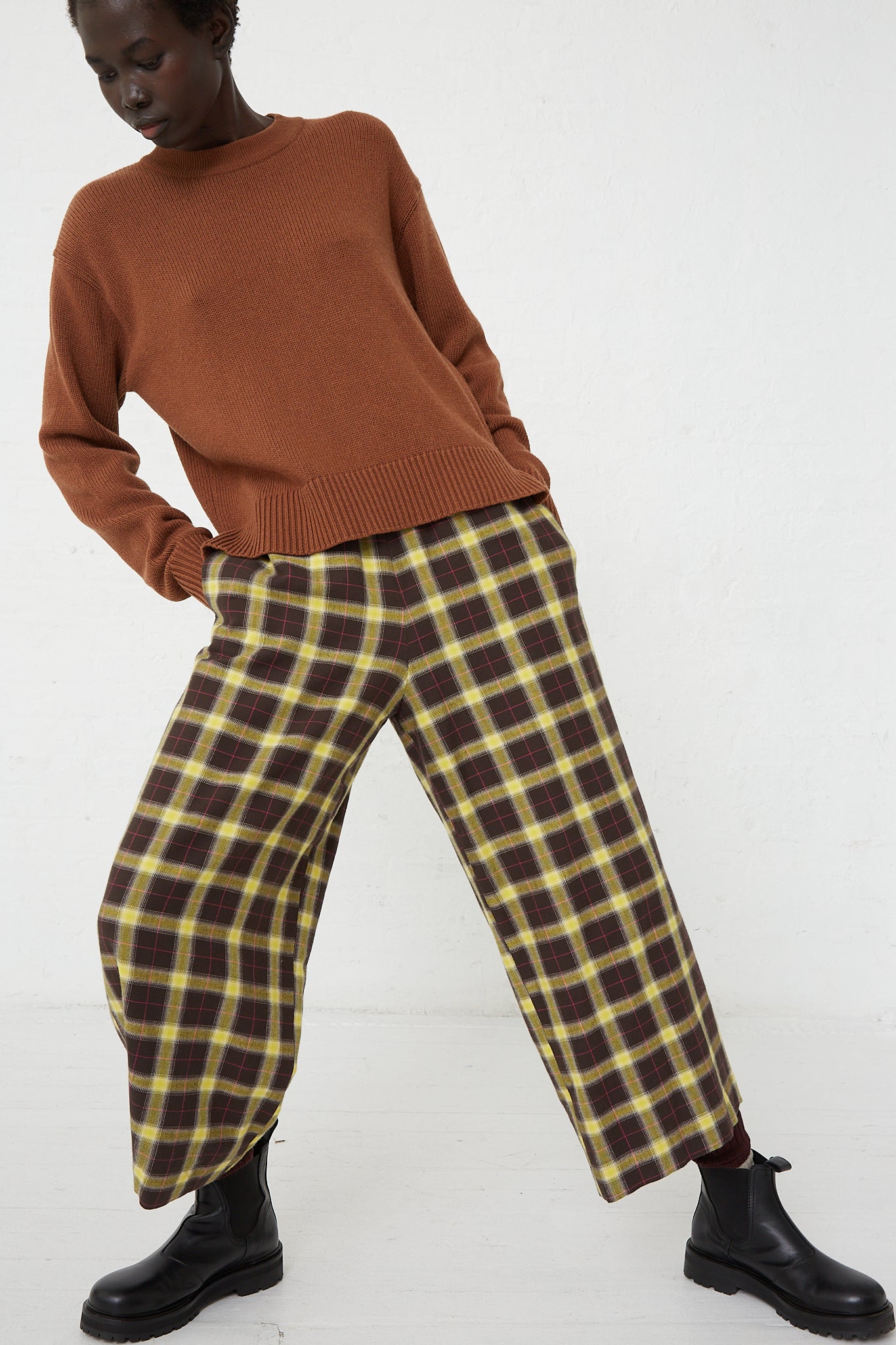 A woman wearing AVN's Easy Pant in Check Brown, Yellow and Pink paired with a relaxed fit brown sweater.