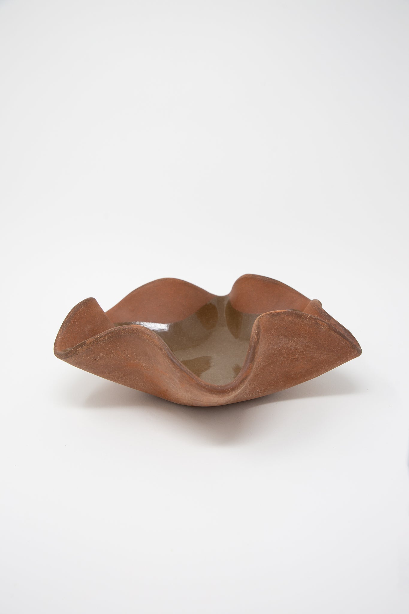 A functional, Lost Quarry hand-built Ruffle Bowl in Terracotta on a white background.