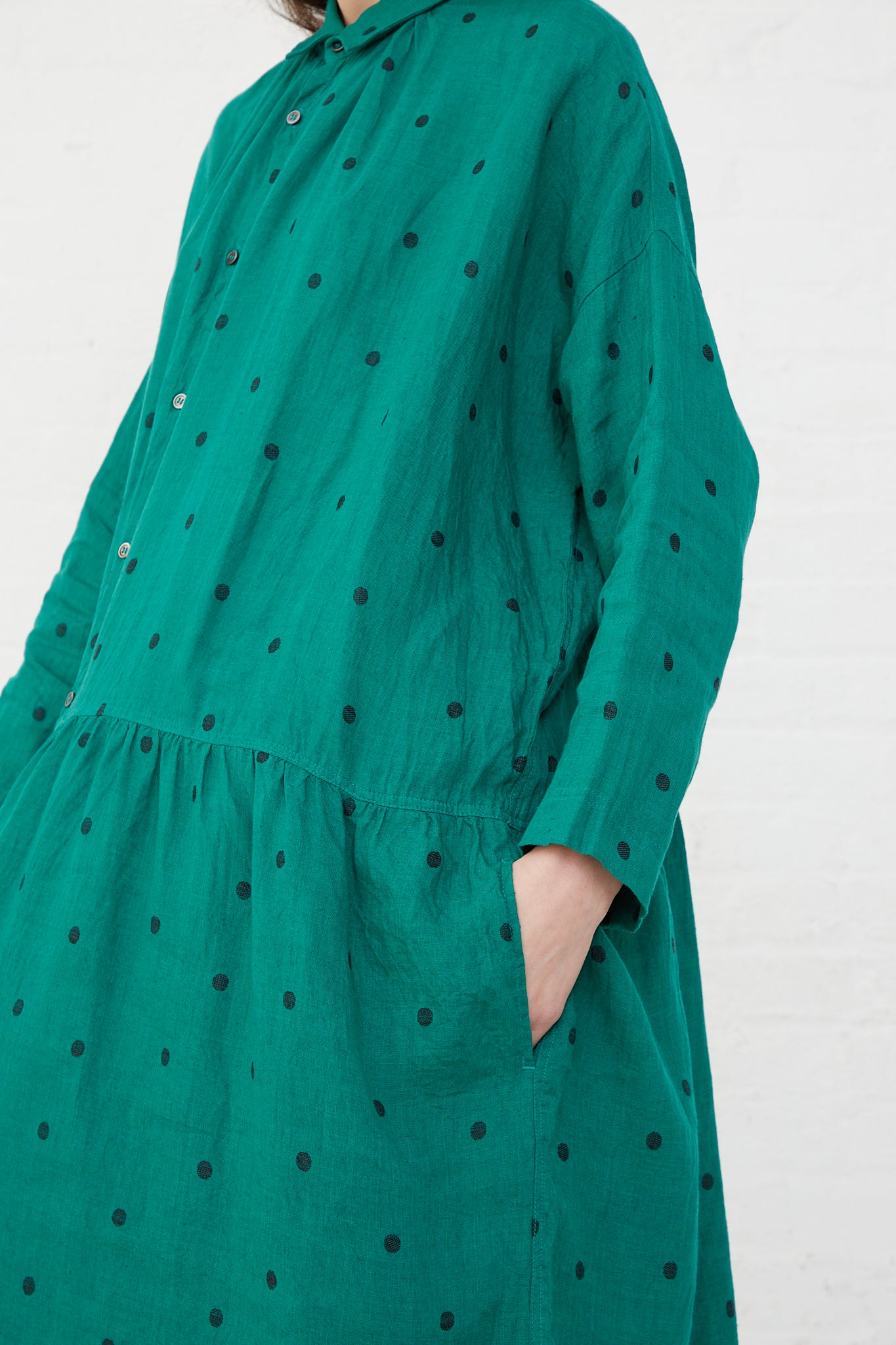 A woman wearing an Ichi Antiquités Linen Dot Dress in Green and Black with gathers at the waist. Side view.