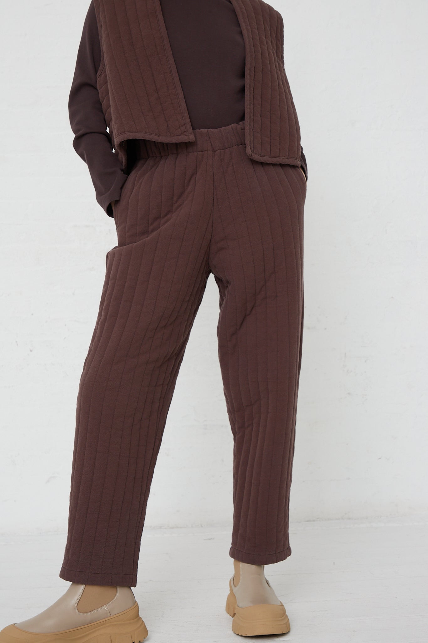 A woman wearing Black Crane's Quilted Easy Pants in Plum made of woven cotton.