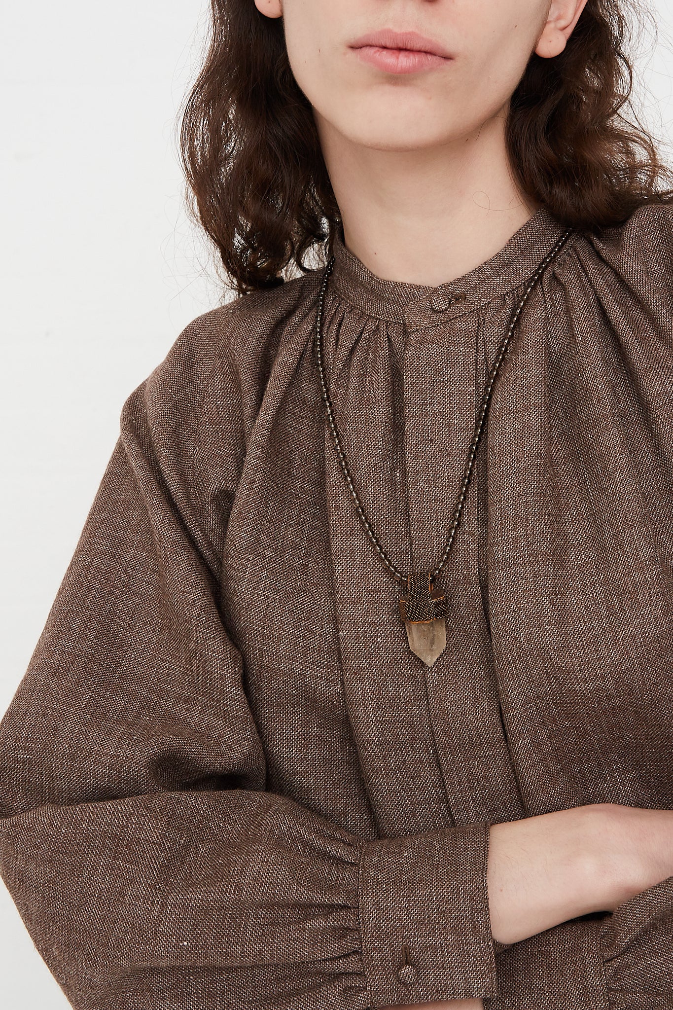 A woman wearing a brown shirt and a Long Pendulum Necklace in Smoky Quartz Beads Brown, Citrine Crystal by Robin Mollicone.