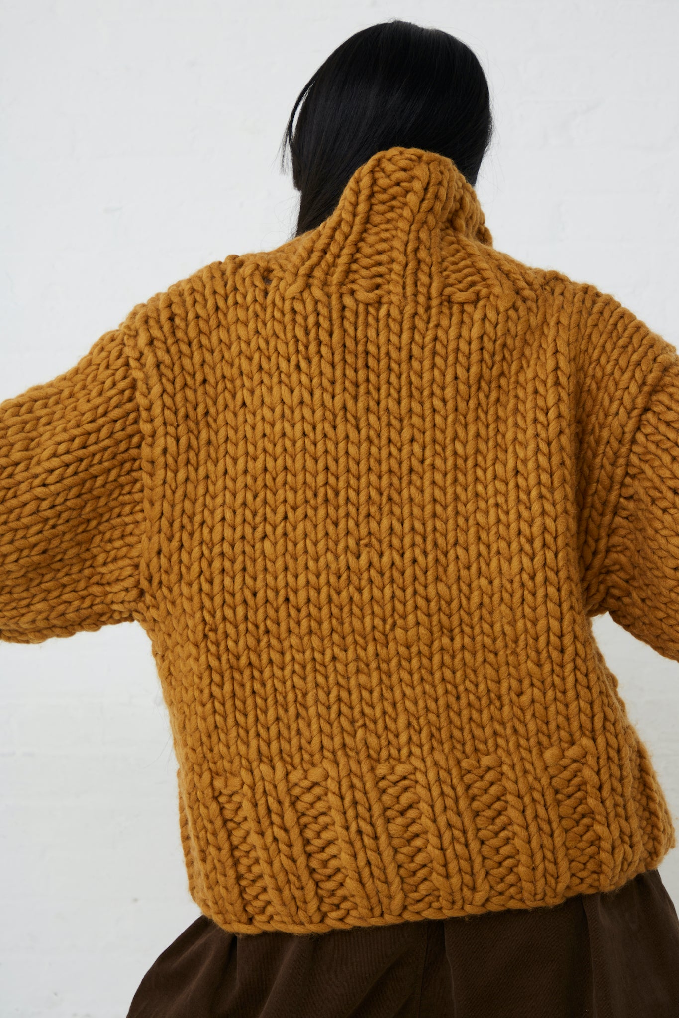 The back of a woman wearing an Ichi hand-knit mustard Wool Hand-Knit Pullover in Mustard turtleneck pullover.