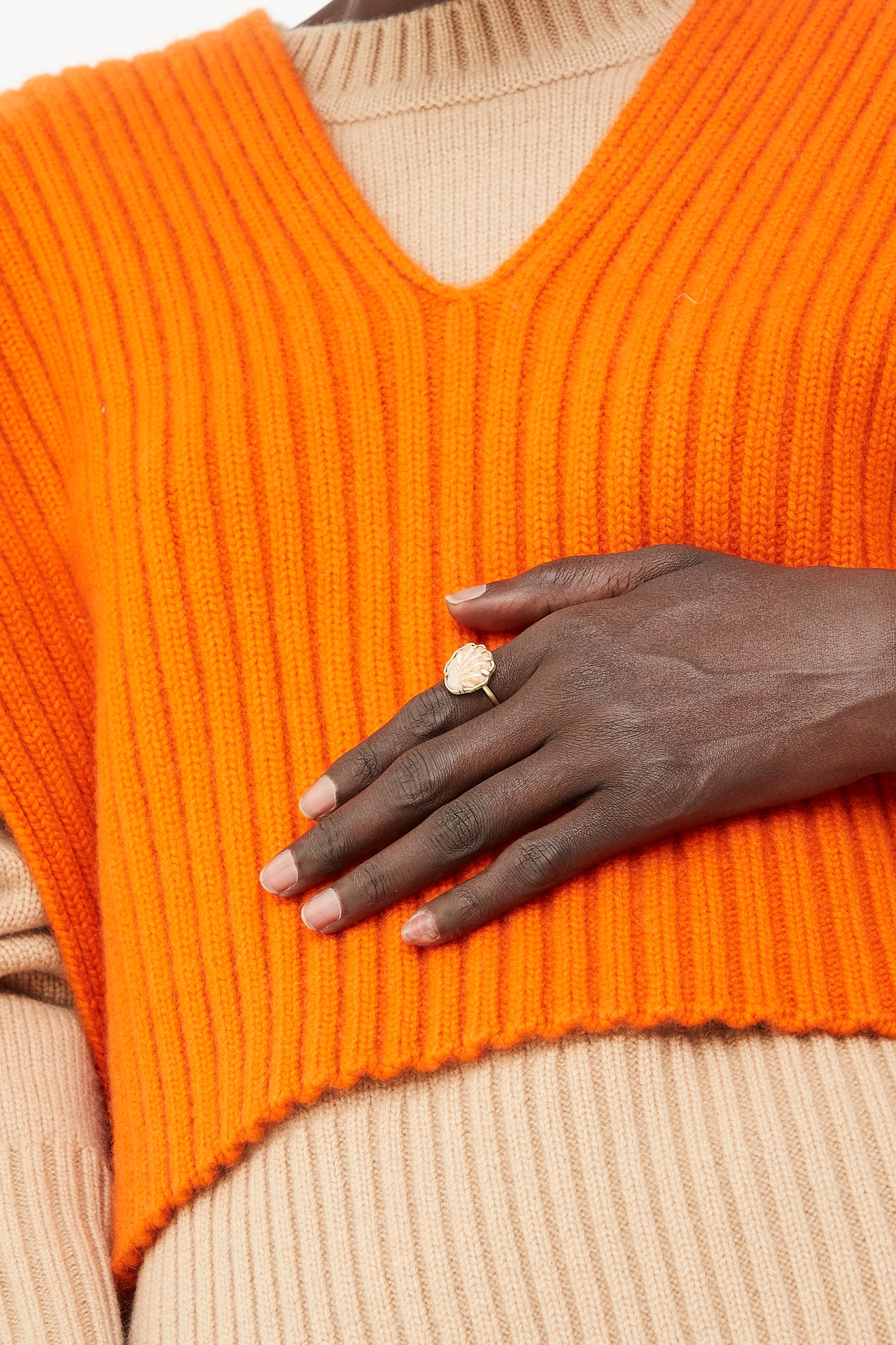 A model showcasing La Ma r brand jewelry, wearing an orange sweater and a 14K Gold Shell Ring 015.