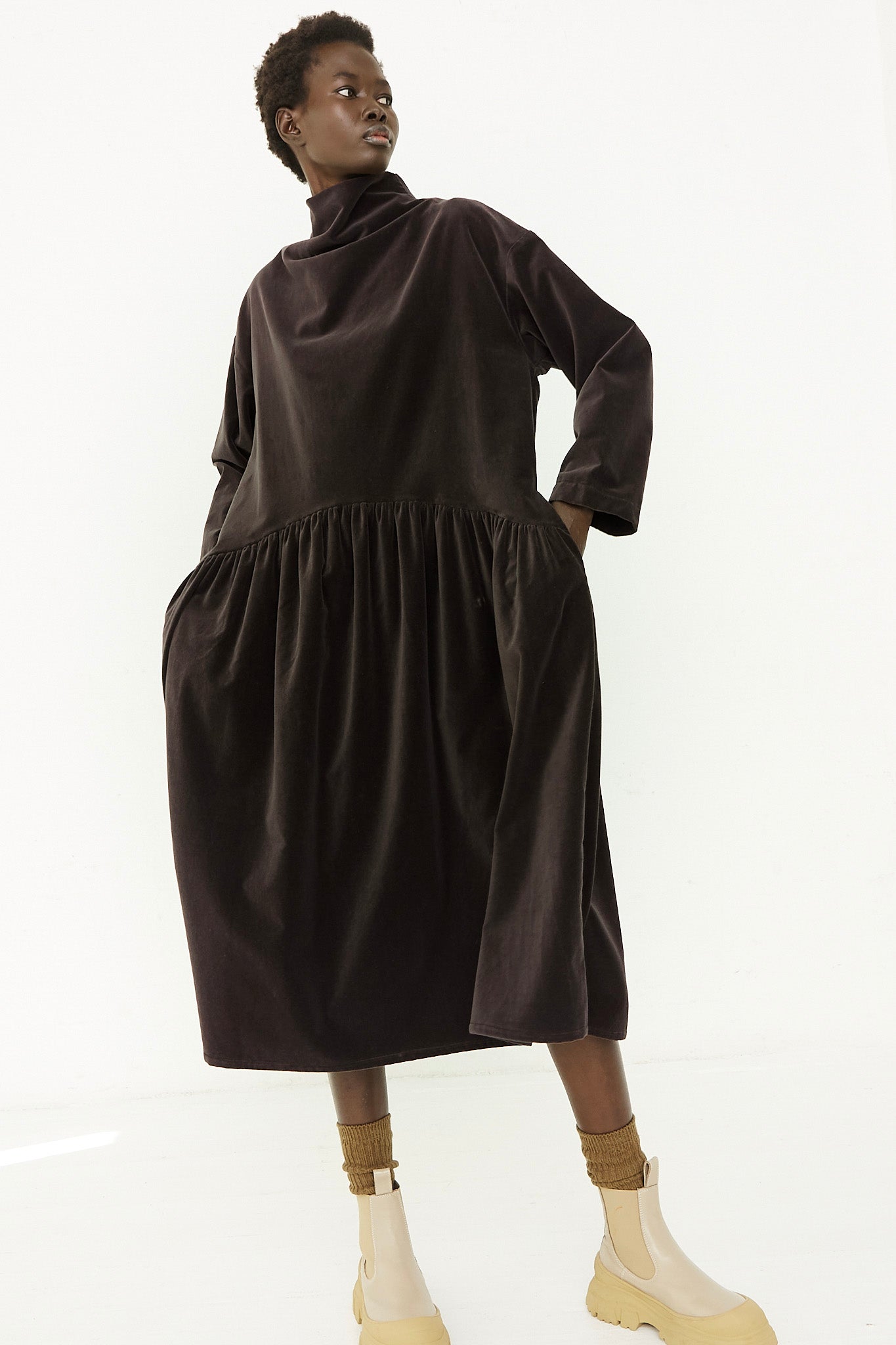 The model is wearing a black dress with a ruffled sleeve.