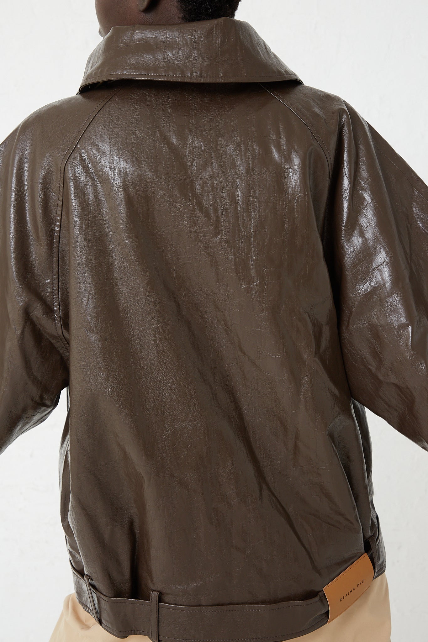 The back of a woman wearing a Rejina Pyo Faux Leather Juno Jacket in Dark Brown.