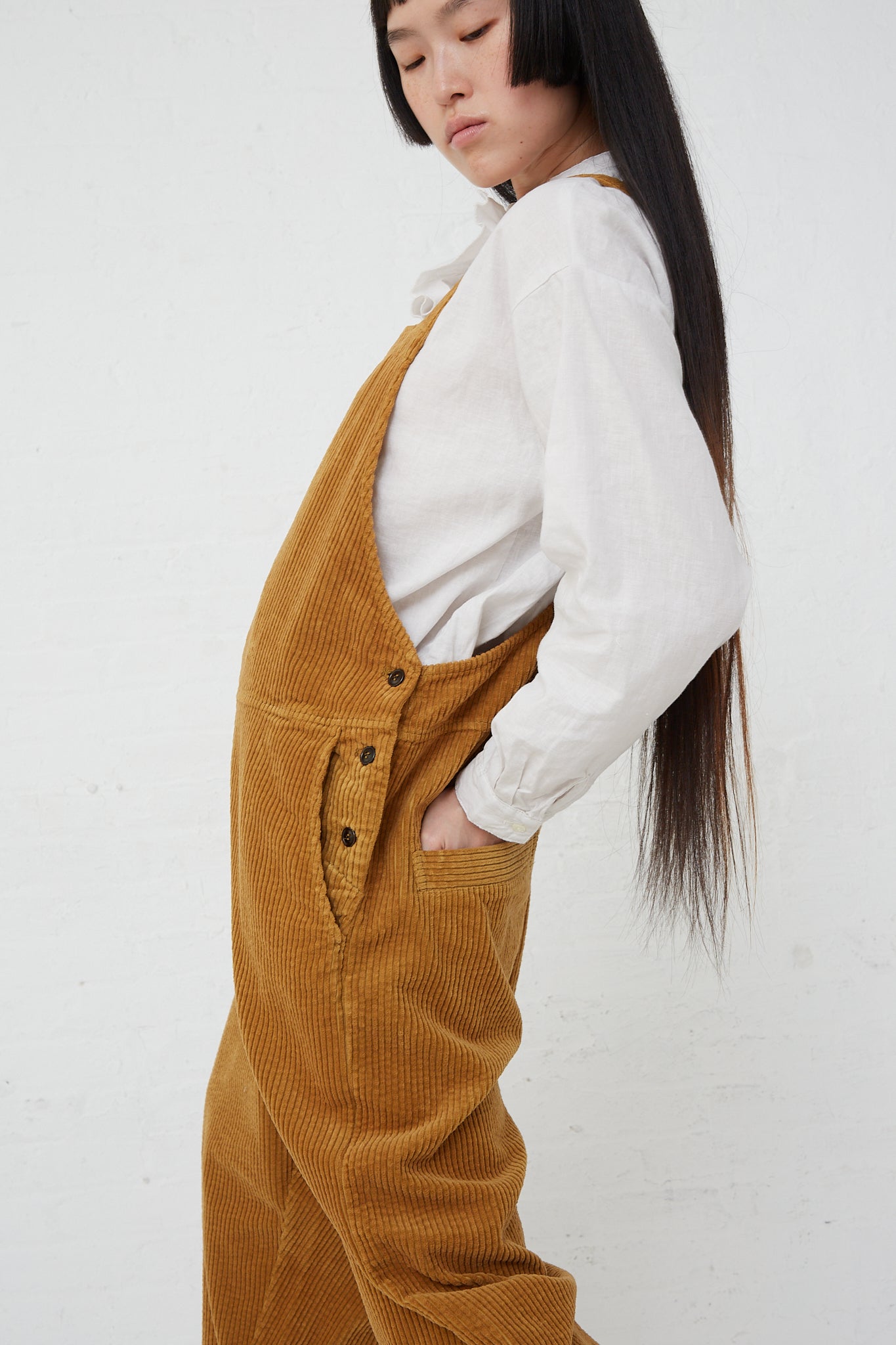 A woman wearing the Cotton Corduroy Overall in Camel by nest Robe. Side view.