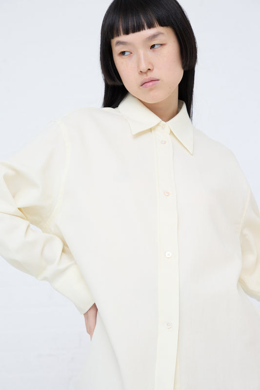 A woman wearing a Santos Overshirt in Parchment by Studio Nicholson with a rounded hem poses for a picture.
