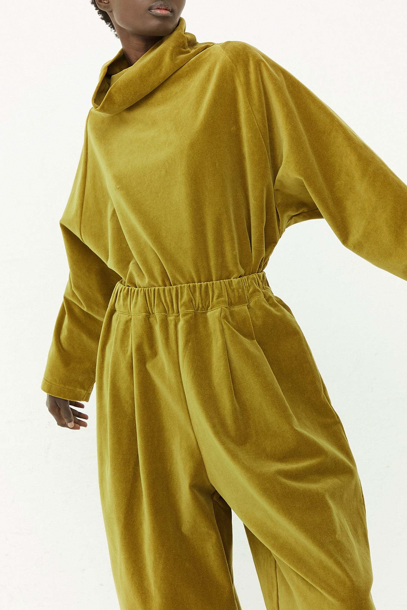 A woman in a yellow Cotton Velveteen jumpsuit with an elasticated waist and wide leg pant from Black Crane.
