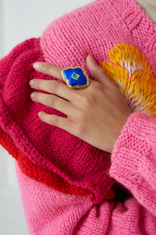 A woman wearing a pink sweater with a Sofio Gongli Ring in Blue with Light Blue Center Square.