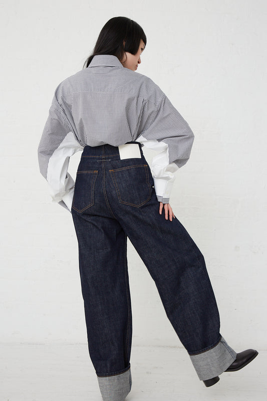 A woman wearing a pair of MM6 5 Pocket Denim Pant in Dark indigo denim and a white shirt. Back view.