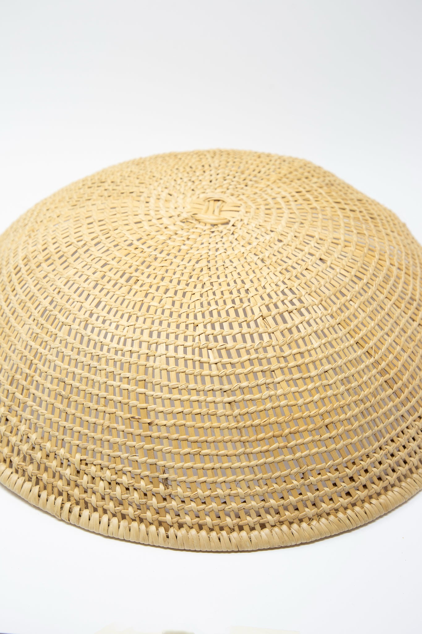 An XL Avia Pova Basket, skillfully woven using traditional techniques, resting on a clean white surface. Upside down view and up close.