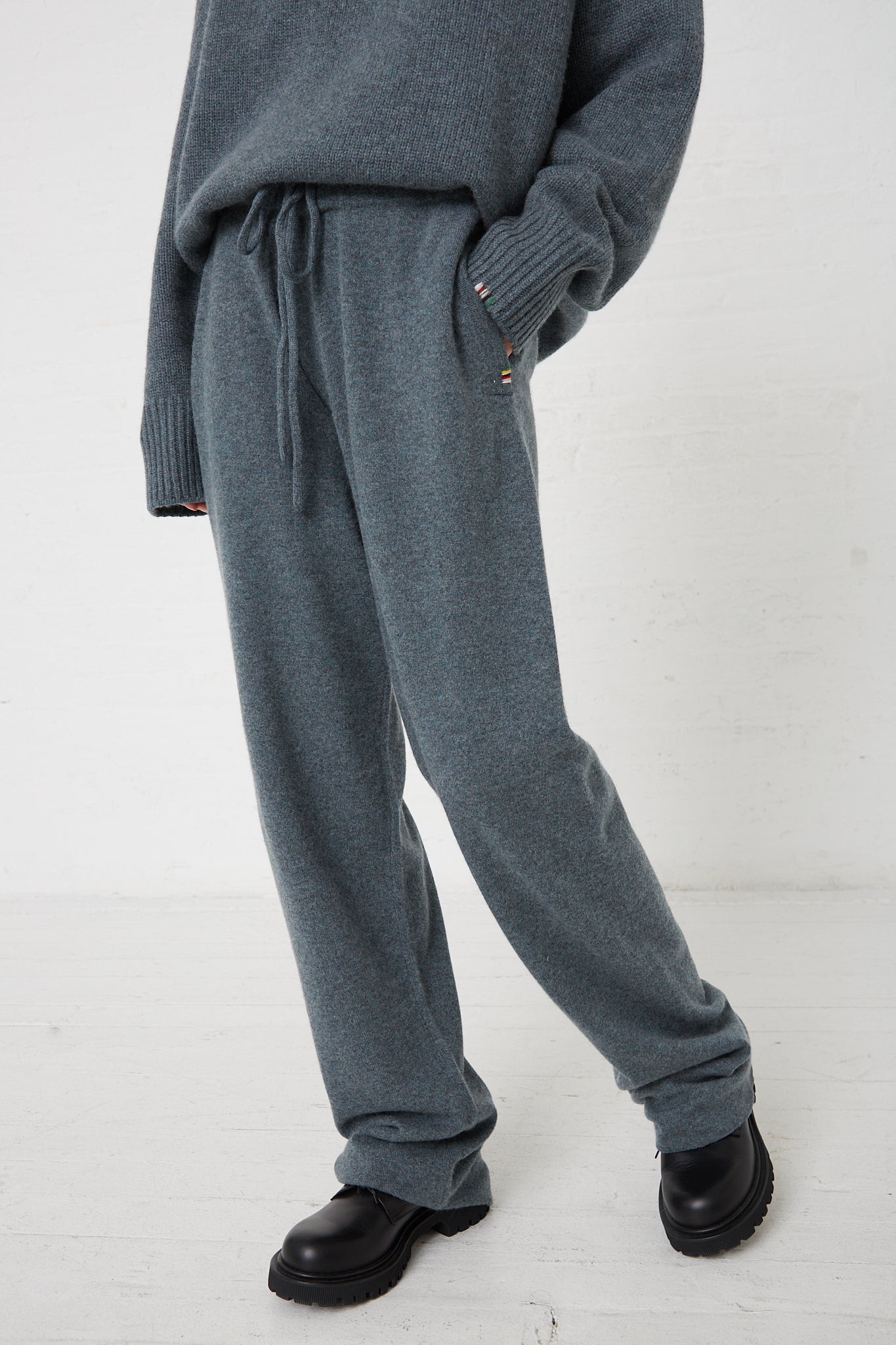 The model is wearing the Extreme Cashmere No. 320 Rush Trouser in Wave with a drawstring waist and grey sweater.