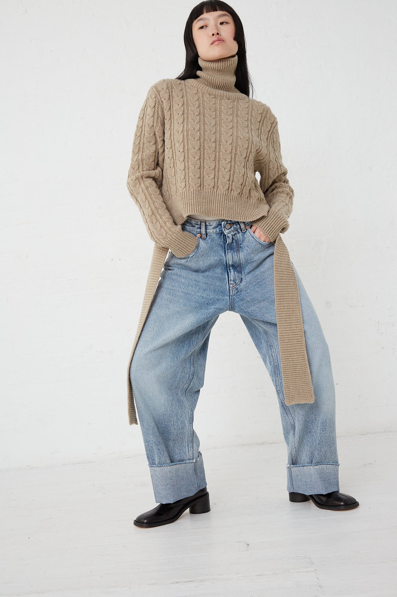 A woman wearing a MM6 5 Pocket Pant in Light Indigo and a turtleneck sweater.