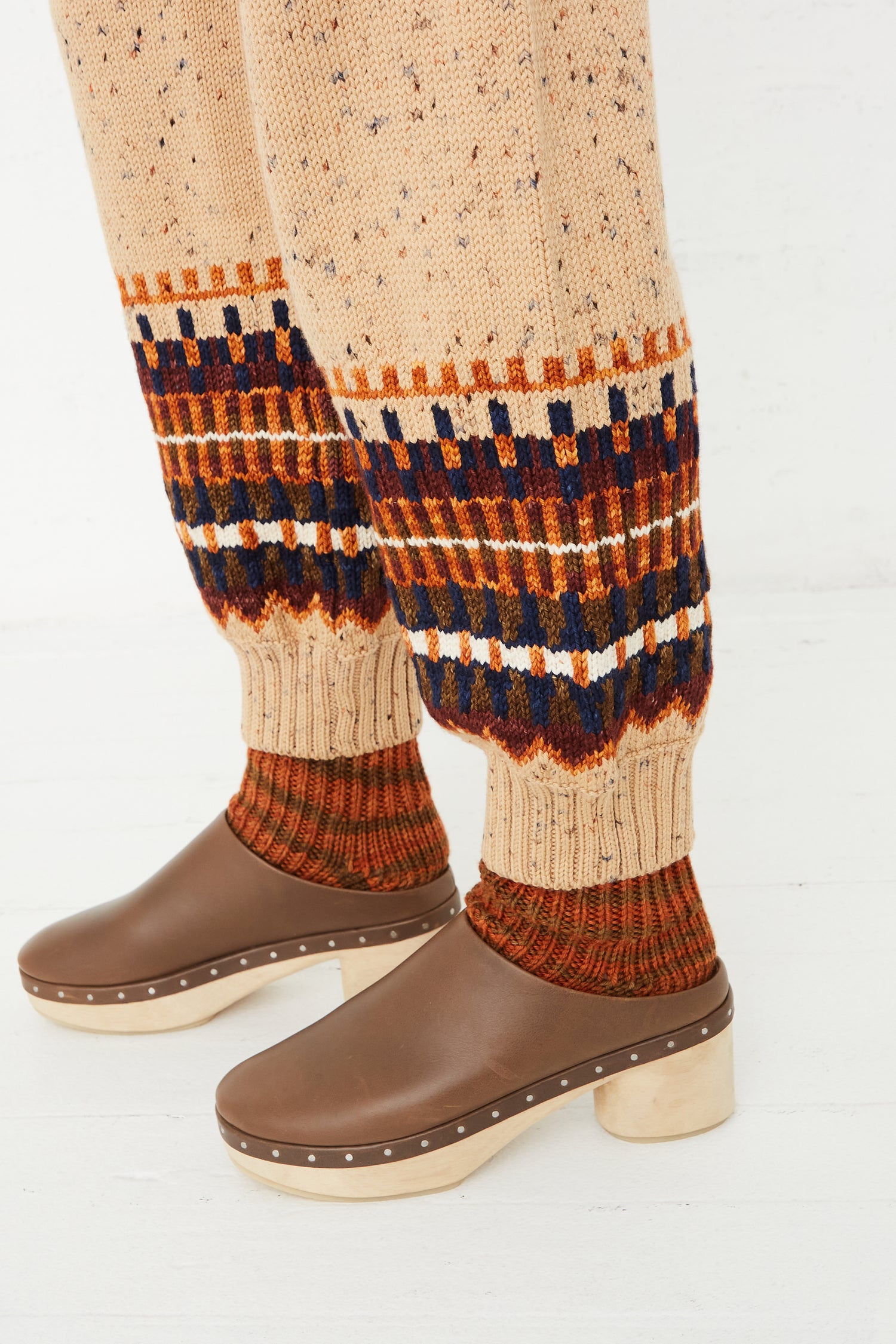 A woman wearing a pair of Fair Isle Warm-Up Pants in Seed Confetti by Misha & Puff and brown boots.