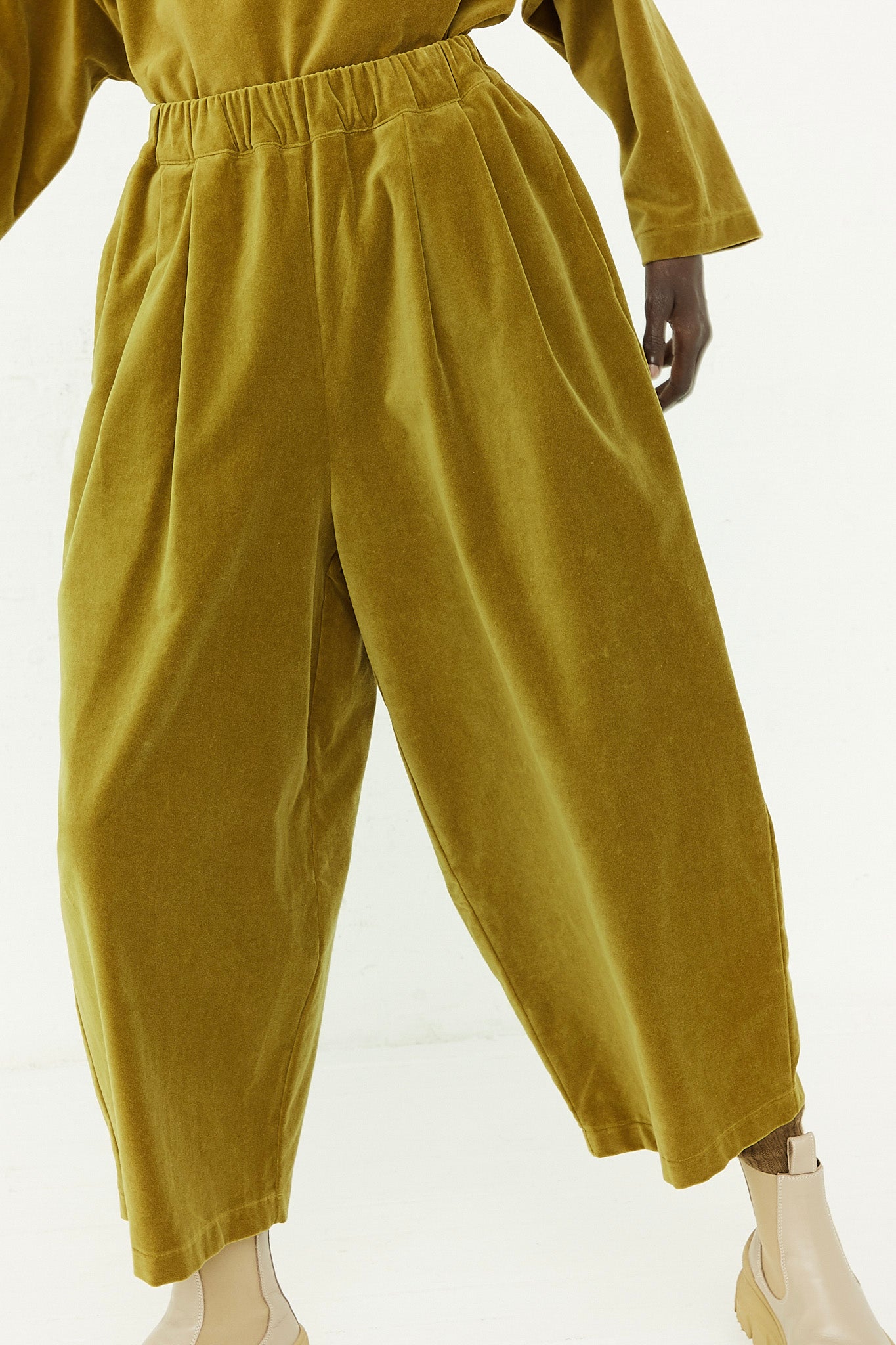 A woman is standing in an olive wide leg jumpsuit with an elasticated waist by Black Crane.