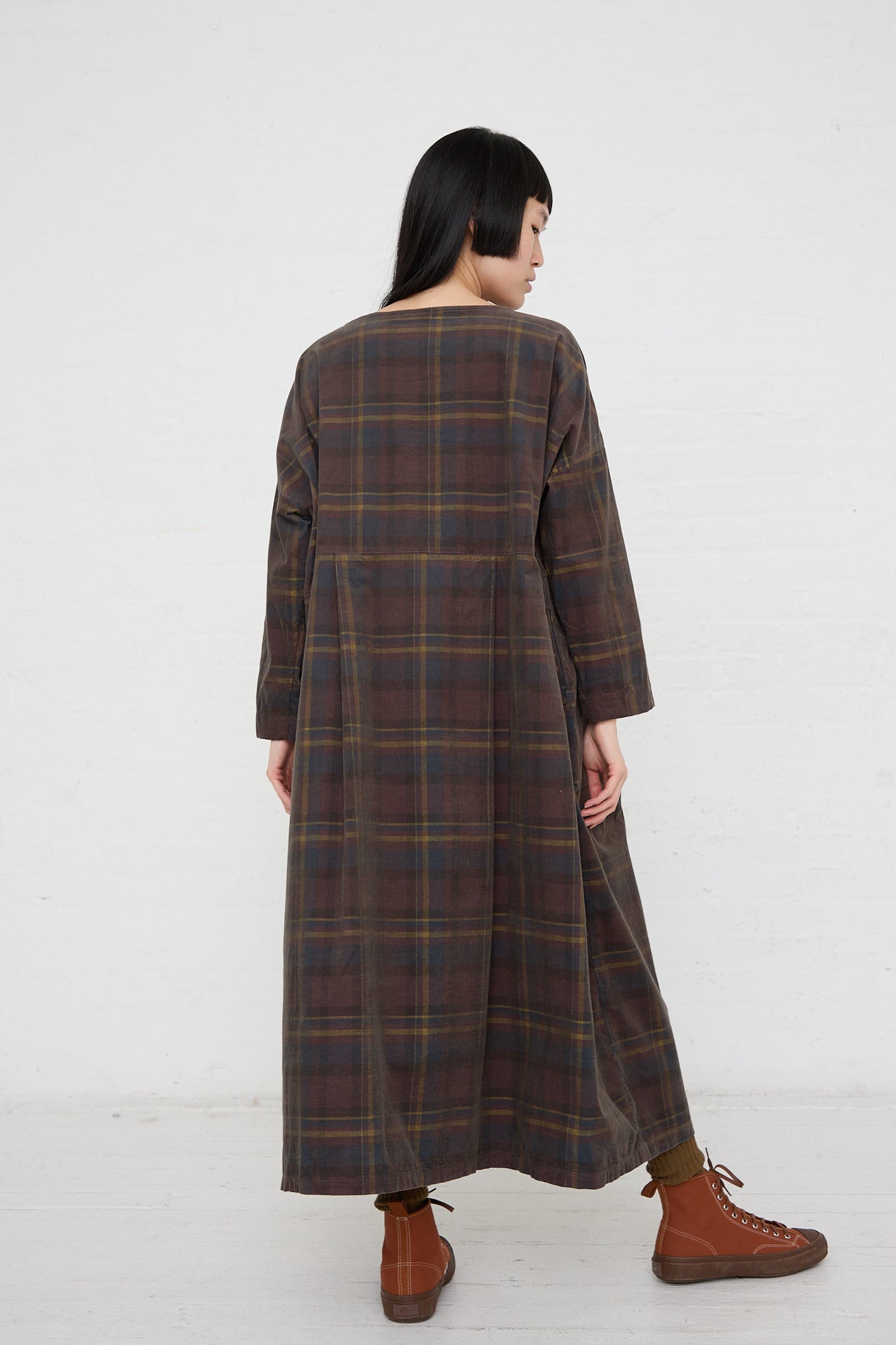 The back view of a woman wearing a relaxed fit Ichi woven cotton dress in brown plaid.