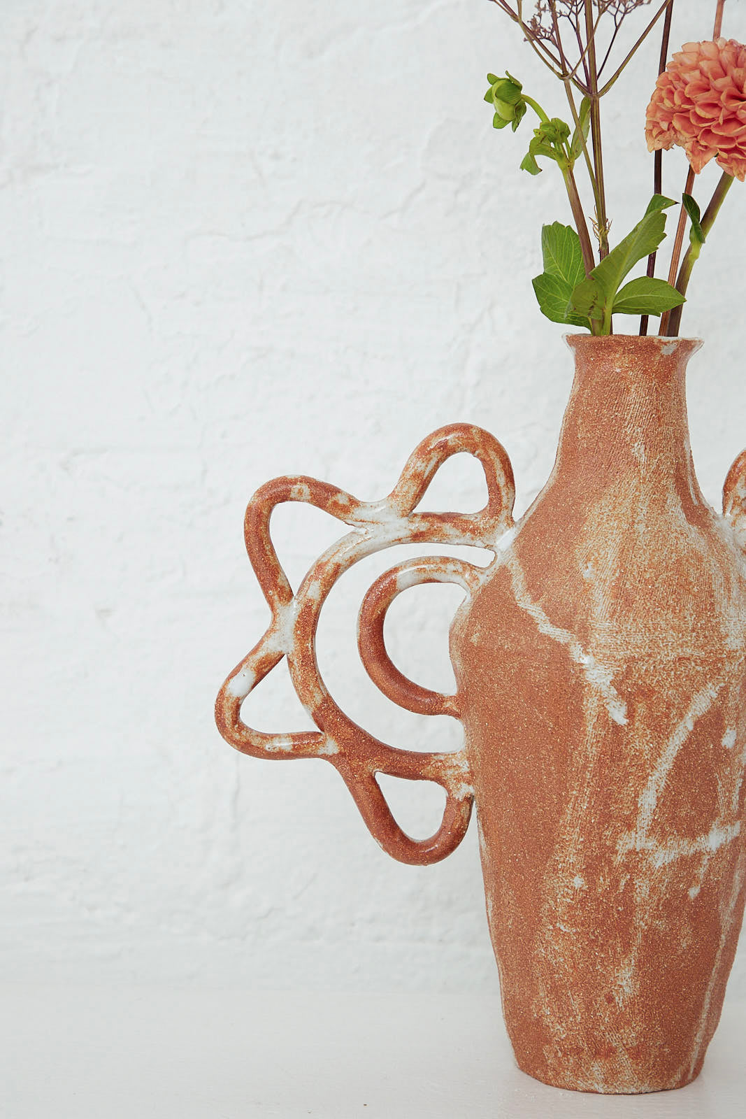 A handmade Tall Amphora Bloom Vase by Clandestine with flowers in it sitting on a table.