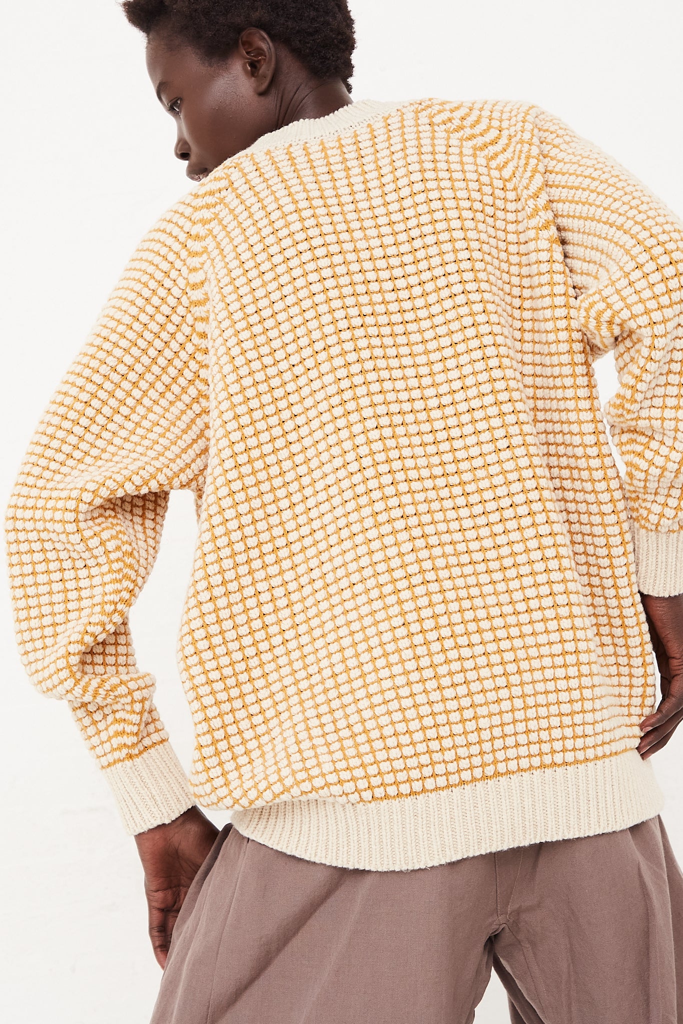 A woman wearing an oversized Jan-Jan Van Essche Crewneck Sweater in Natural Gold Lalin.