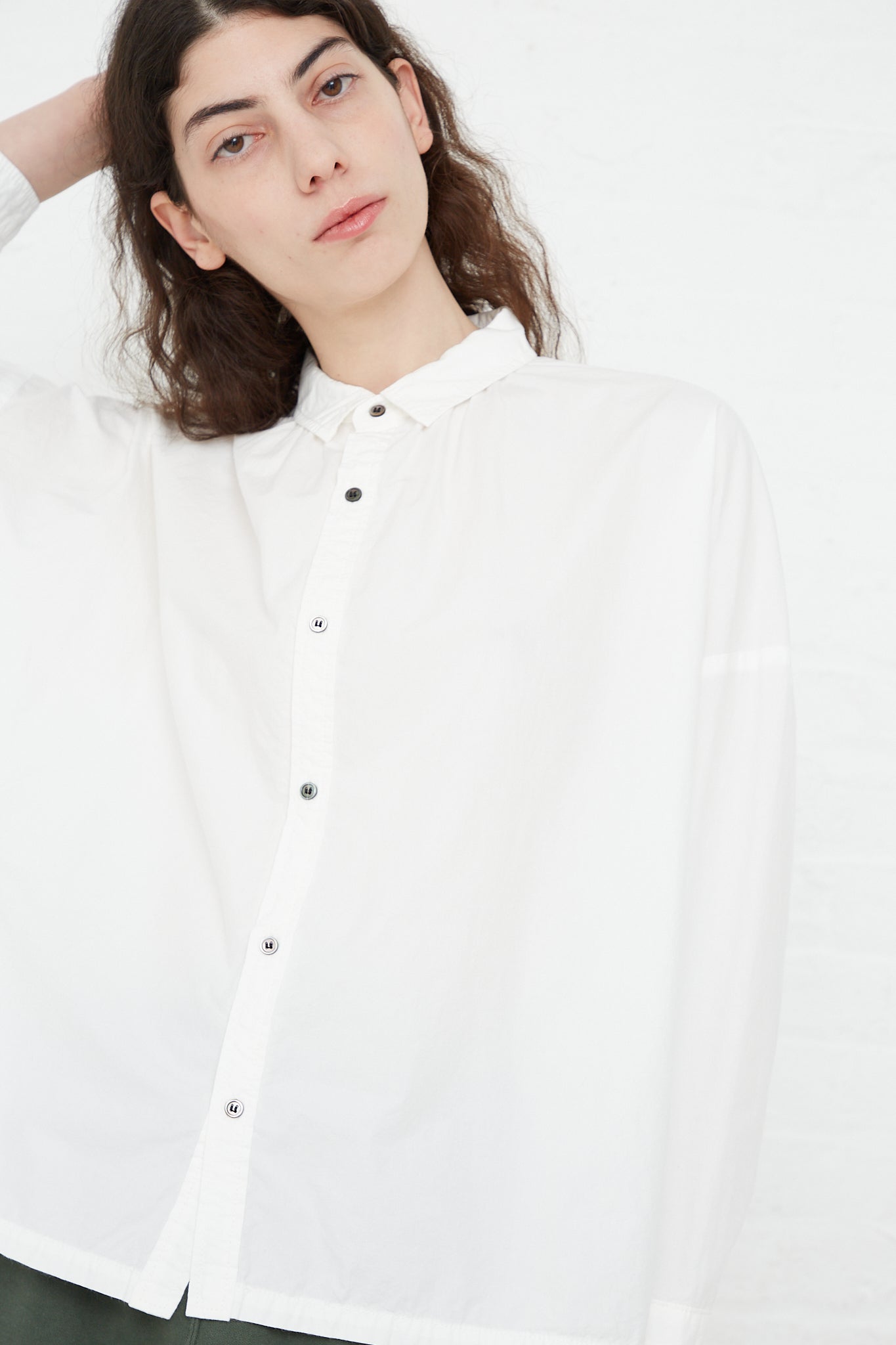 A model wearing a Woven Cotton Oumisarashi Shirt in White by Ichi Antiquités and green pants made of natural fibers.