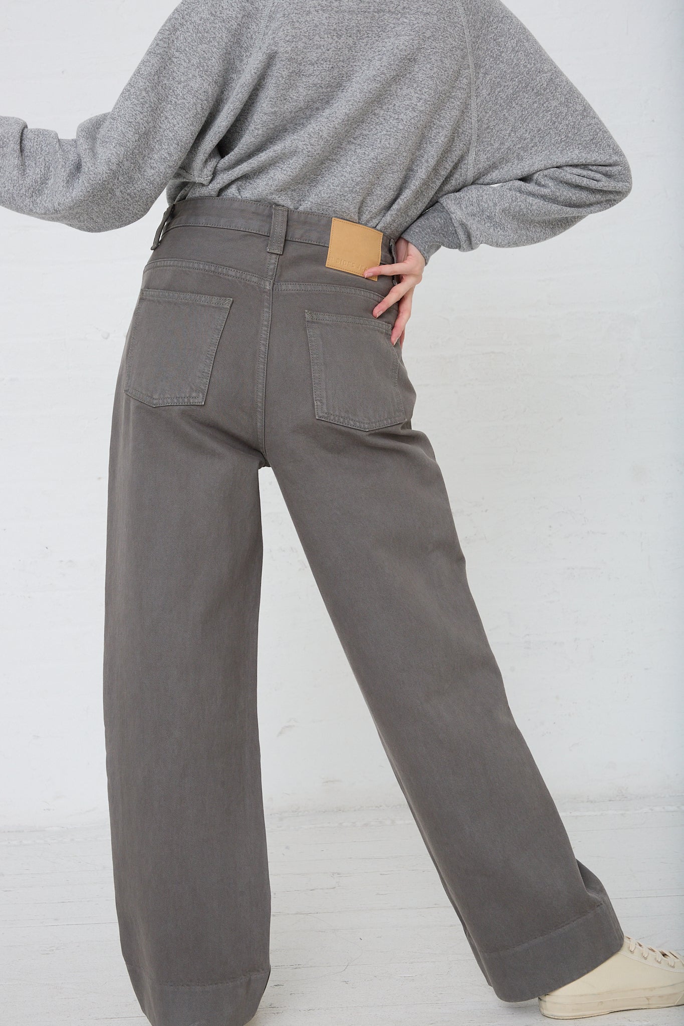 A model wearing the B Sides Easy Mid Relaxed Jean in Olive Overdye. Back view.