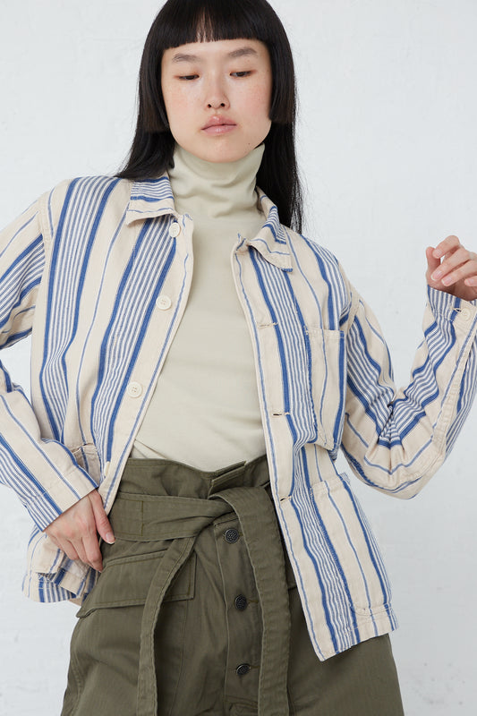 The model is wearing an As Ever Henri Jacket in Vintage Blue Stripe made of cotton textile. Jacket opened. Front view.
