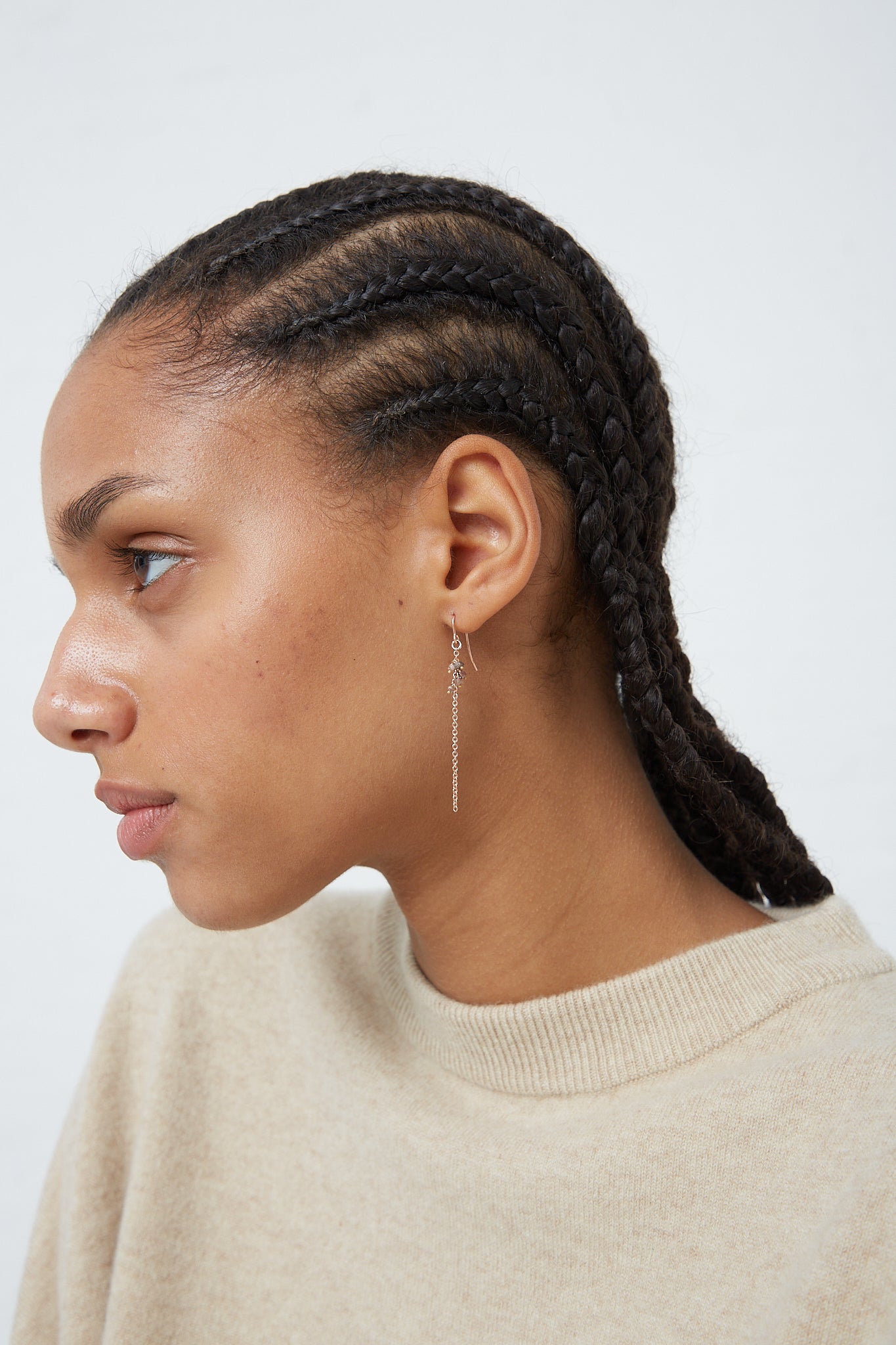 A woman wearing Stephanie Schneider's rose gold plated and raw brown diamond earrings with braided hair and a pair of earrings.