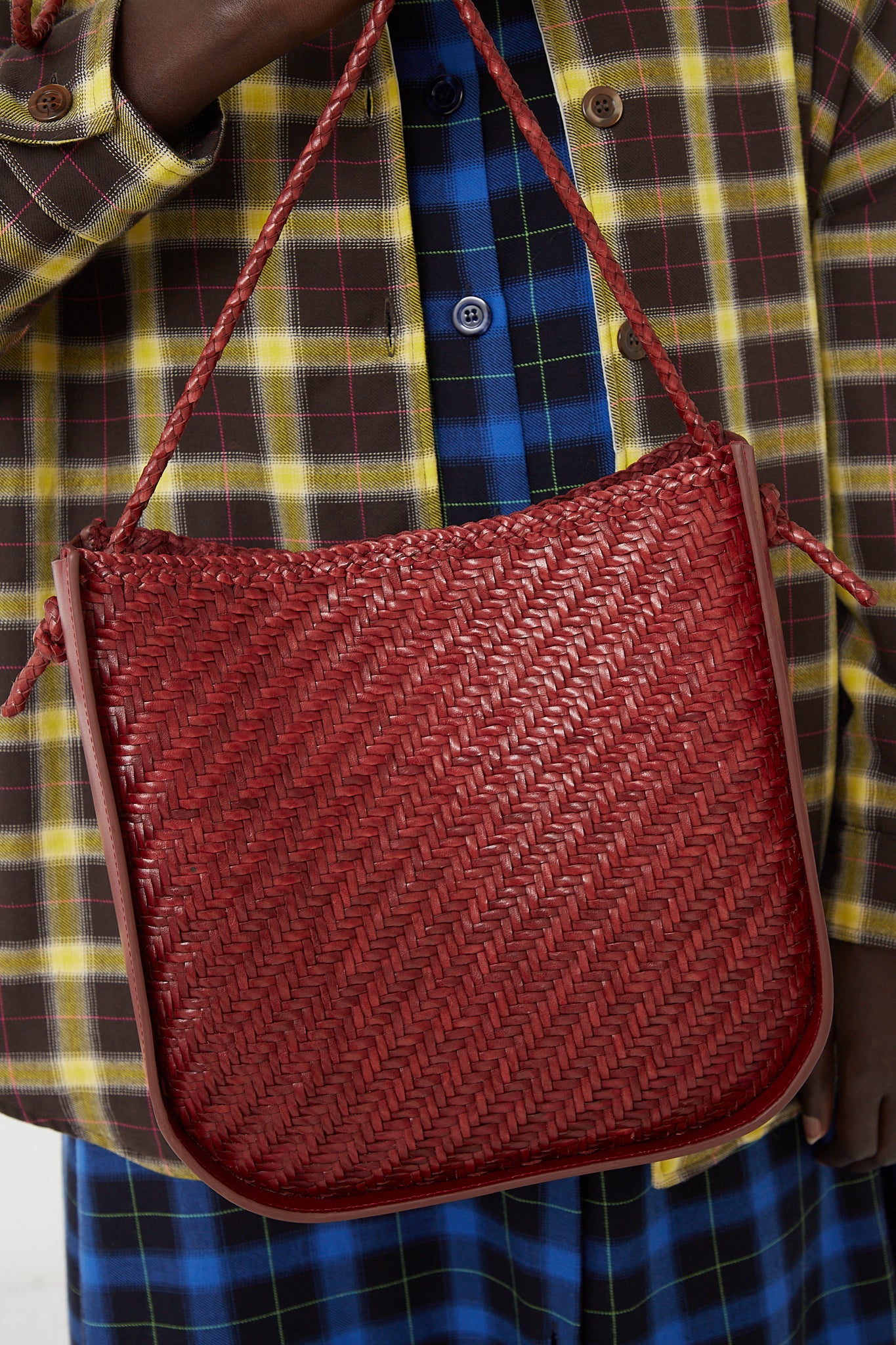 The woman is holding a red Dragon Diffusion Wanaka Crossbody Bag in Bordo.