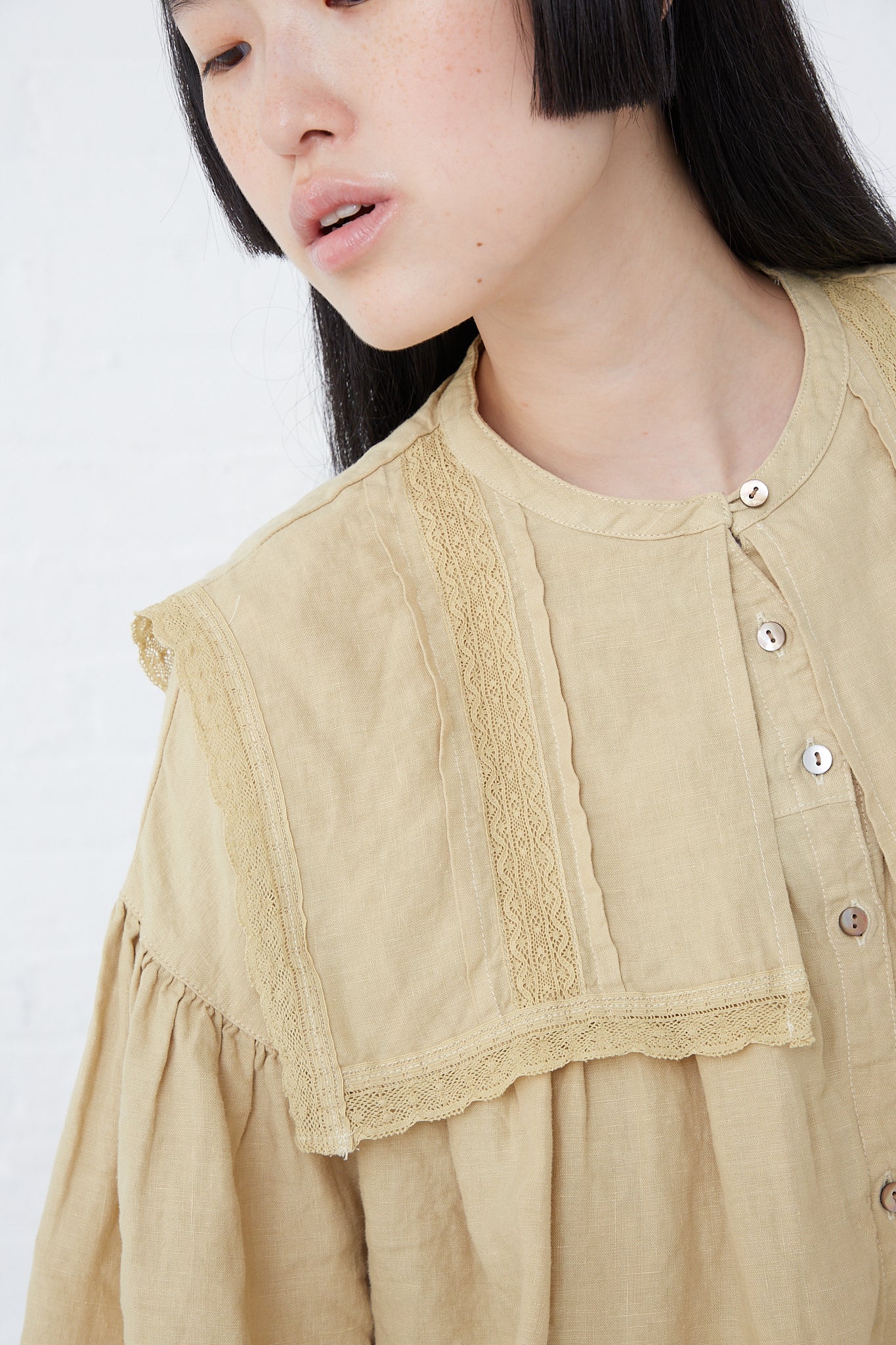 A woman wearing a Natural Dyed Linen Lace Blouse in Yellow crafted from nest Robe.