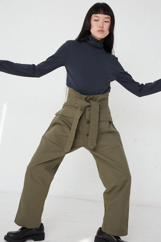 A woman in As Ever's Olive Tie Tanker pants and a black turtle neck.