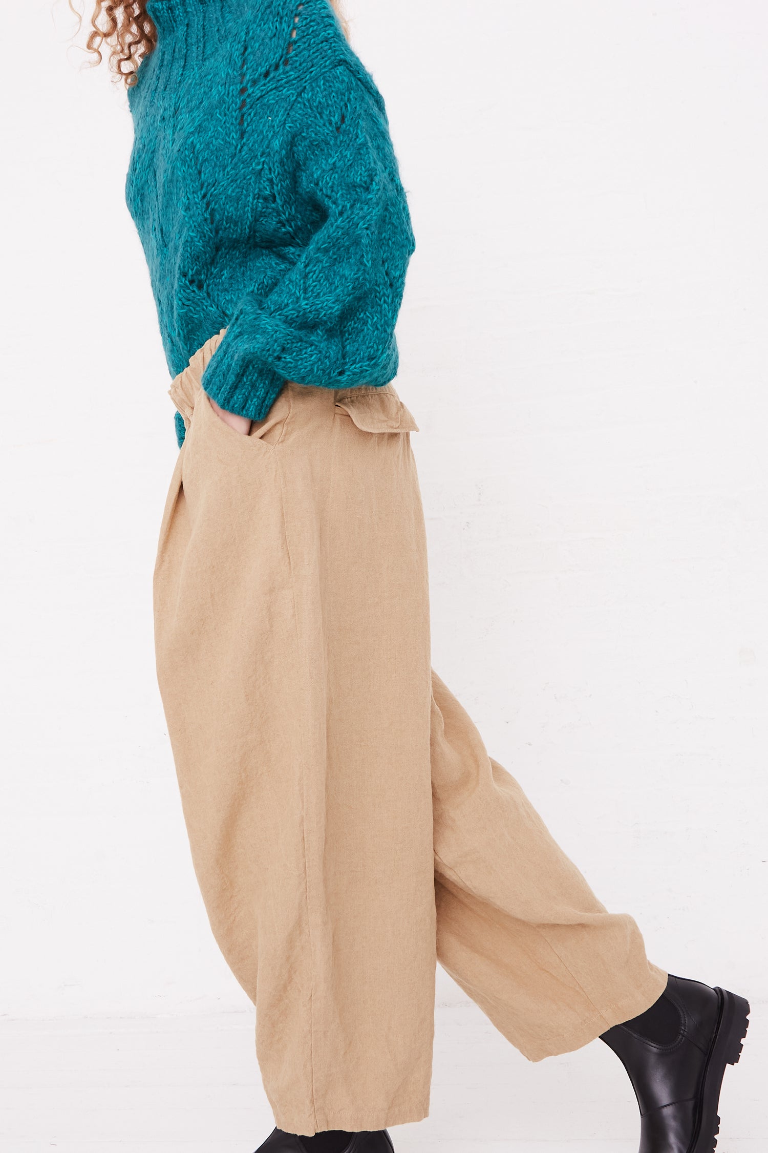 A side view of a model in a teal sweater and relaxed fit Linen Canvas Pants in Beige from Ichi Antiquités.