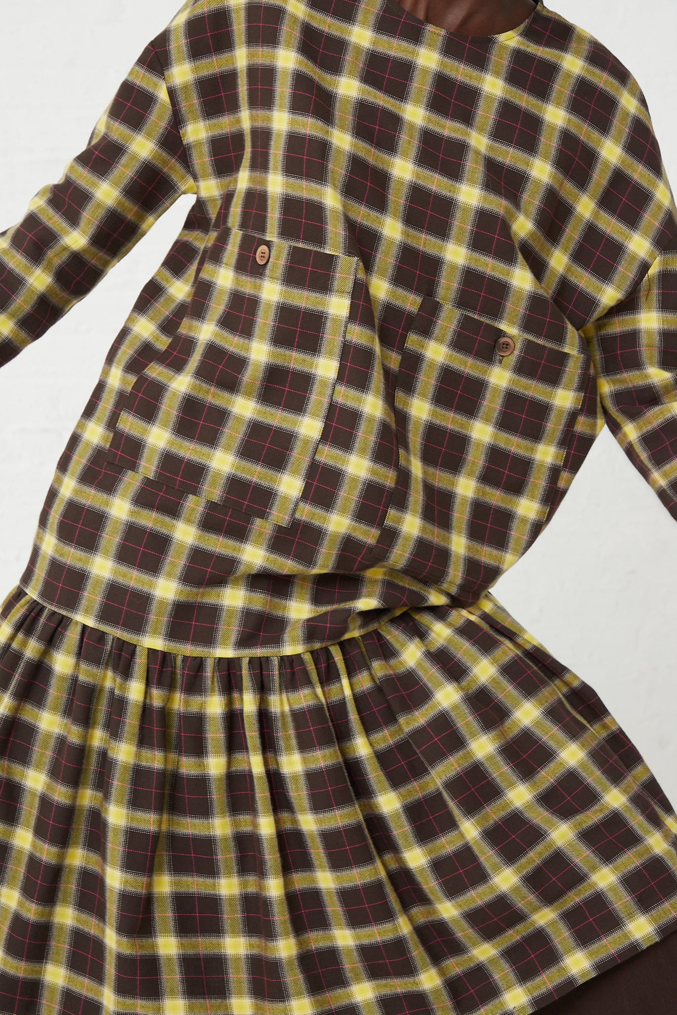 A woman wearing an AVN Fun Dress in Check Brown, Yellow and Pink with oversized patch pockets in yellow and brown plaid.