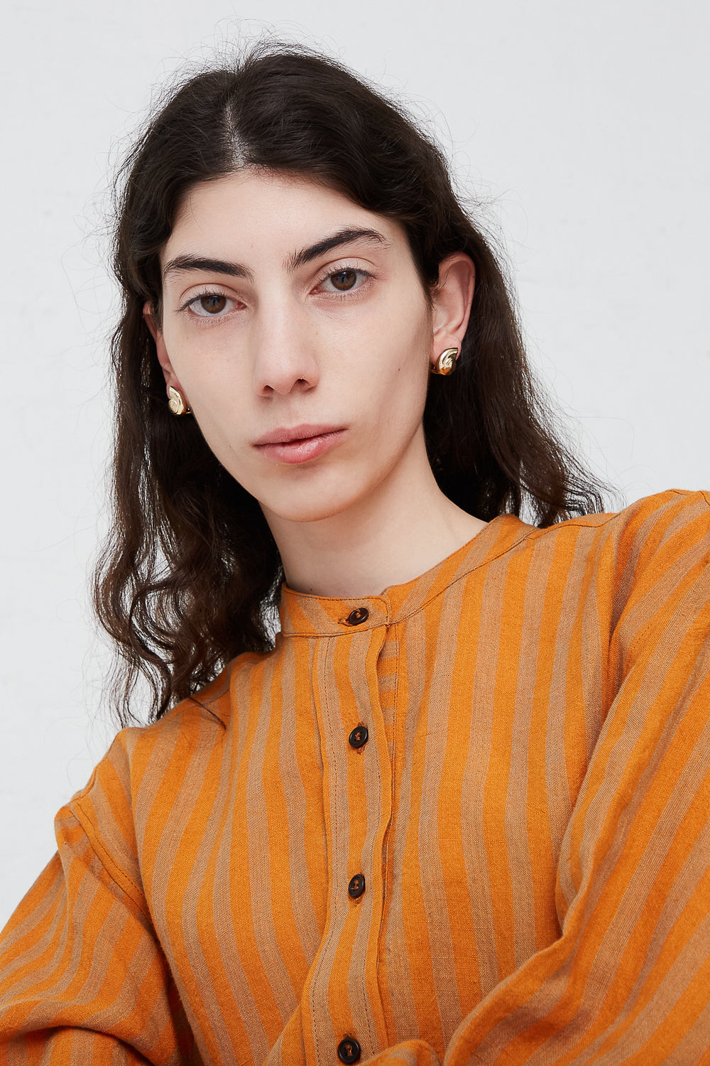 A woman in an orange striped shirt posing for a photo wearing Kathryn Bentley's Large Nautilus Earrings made in Los Angeles.