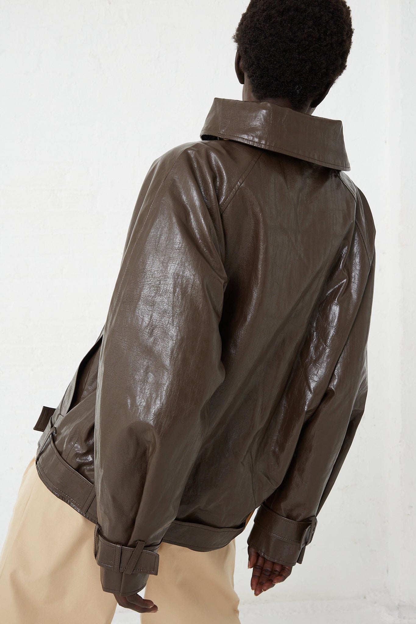 The back of a woman in a Rejina Pyo Faux Leather Juno Jacket in Dark Brown.