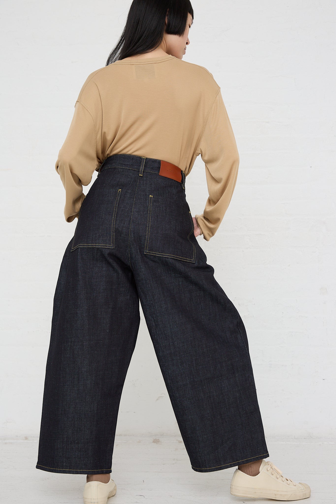 The back view of a woman wearing an oversized fit denim Chalco Wide Crop Jean in Raw Indigo by Studio Nicholson.