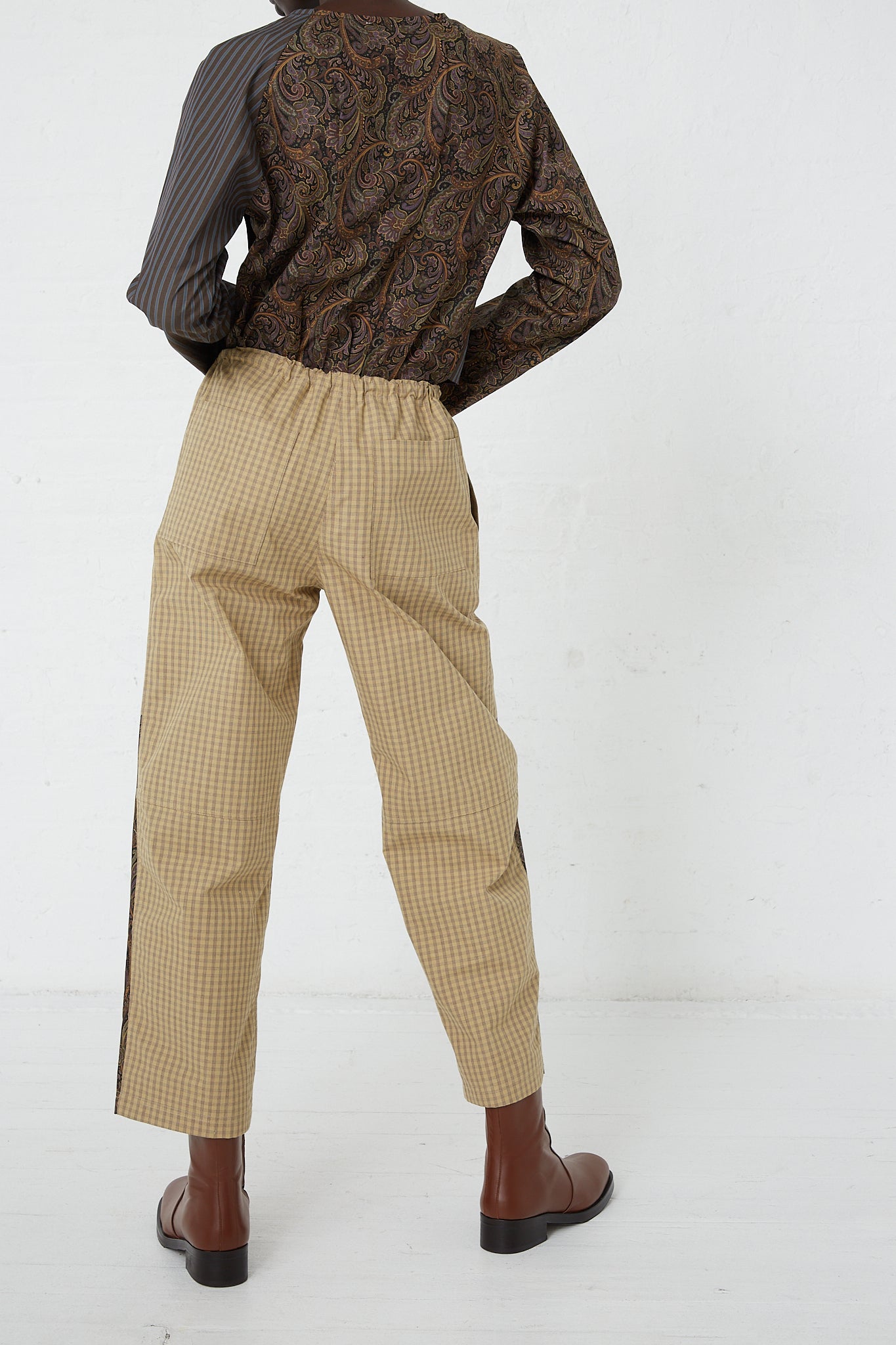 The back of a woman wearing SC103 striped pants and a paisley top, effortlessly accessorized with an adjustable waist belt for added style and comfort.