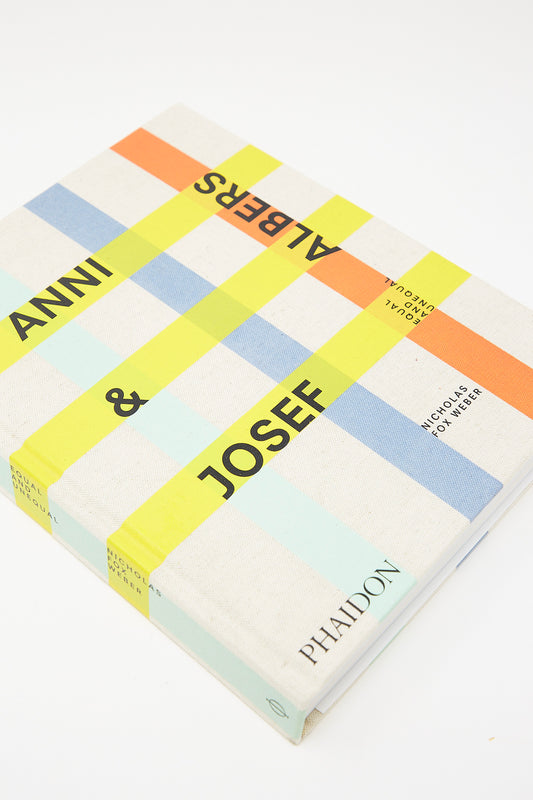 A book titled "Anni & Josef Albers: Equal and Unequal" by Nicholas Fox Weber, published by Phaidon, with a multicolored grid cover design, explores the works of textile artist Anni Albers and