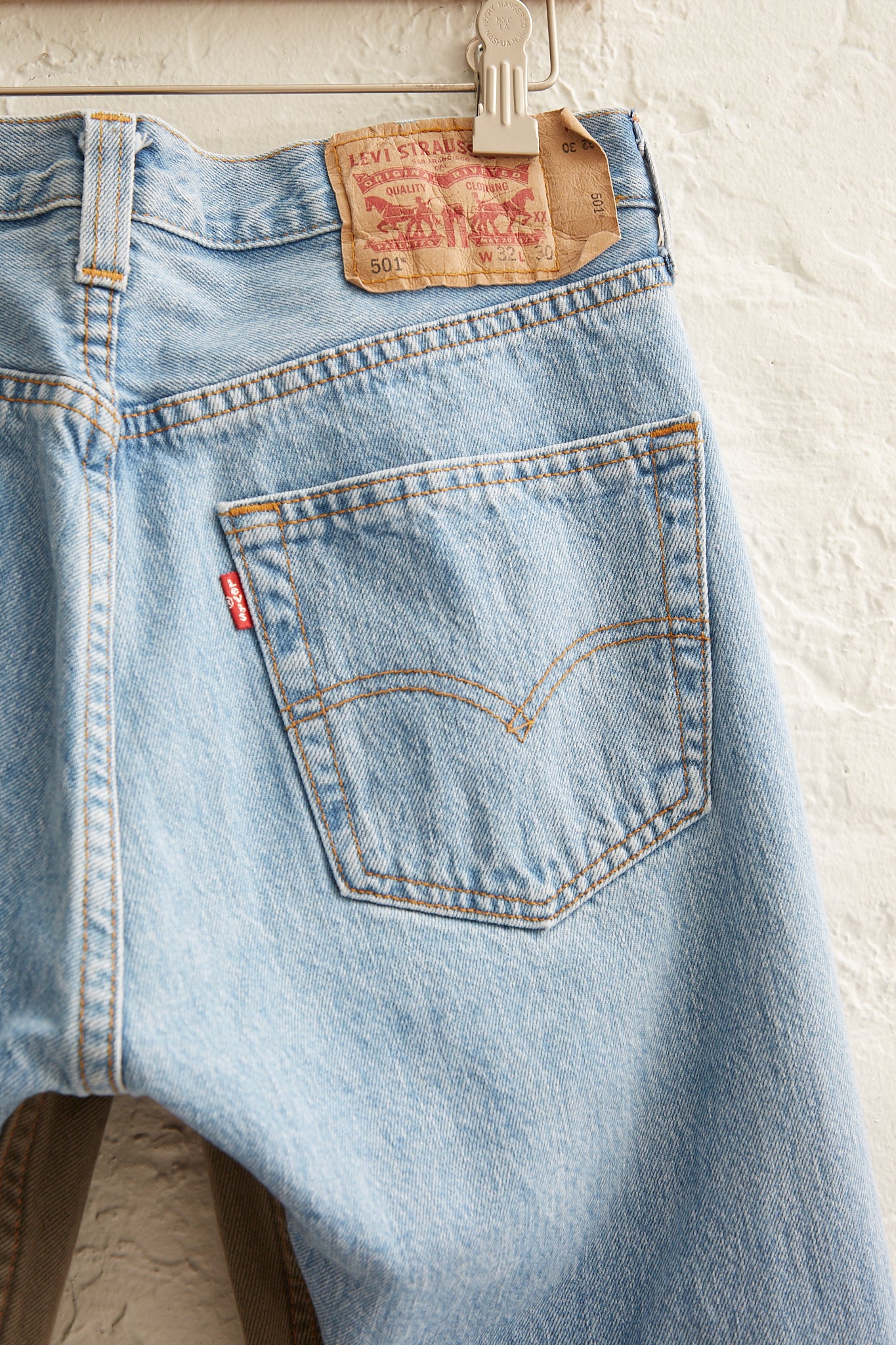 A pair of upcycled vintage Bless Jeanspleatfront No. 73 in Surprise Color Mix A hanging on a hanger, featuring a 5-pocket design. These mid-waist jeans are a timeless addition to any wardrobe.