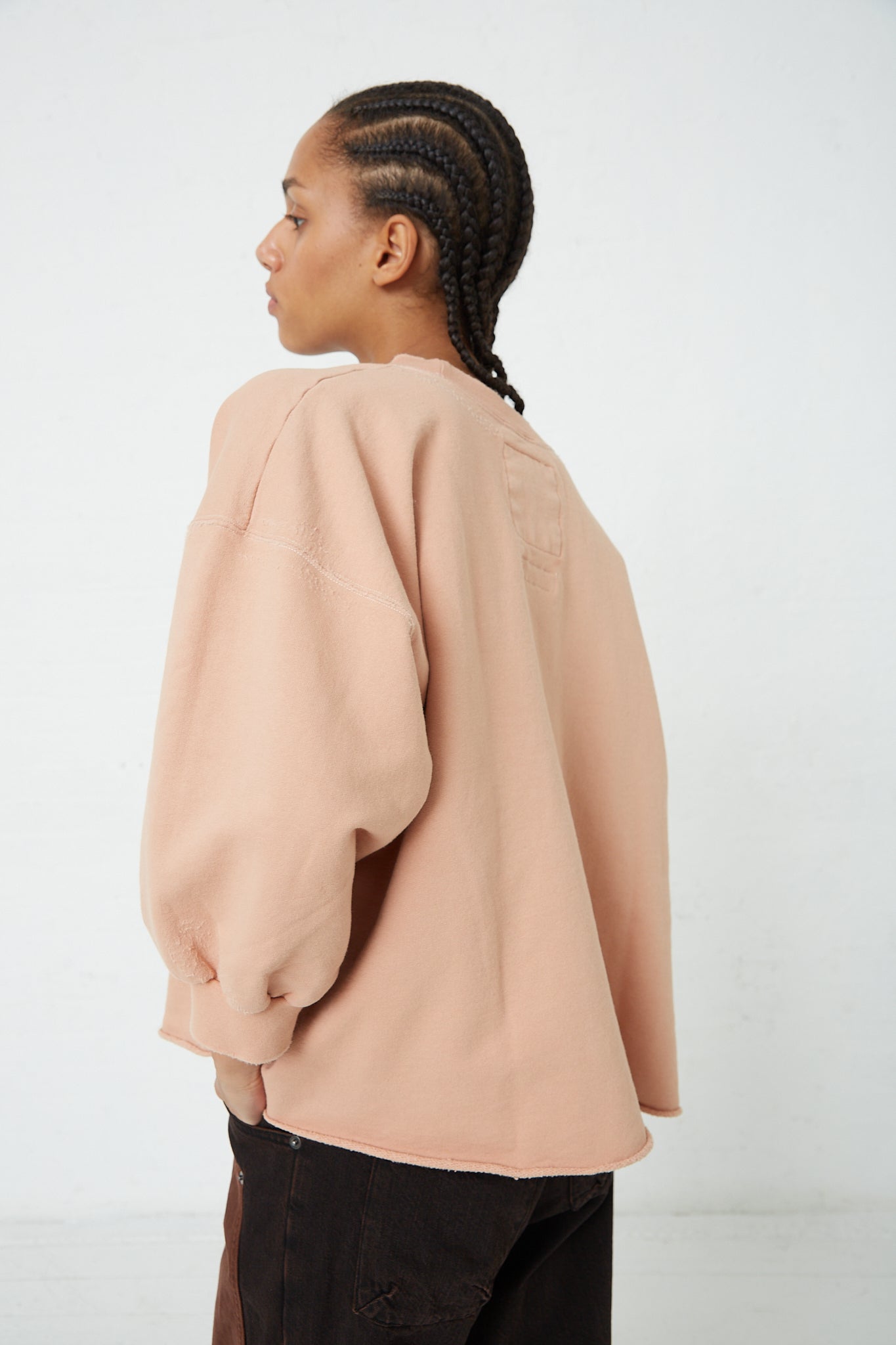 The back of a woman wearing a Rachel Comey Fond Sweatshirt in Fawn with a raw edge hemline.