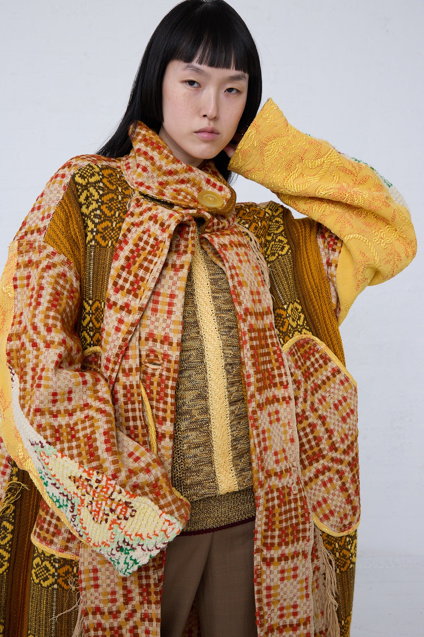 A woman in a Thank You Have A Good Day Patchwork Blanket Scarf Parka in Red, Yellow and Brown, posing for a photo.