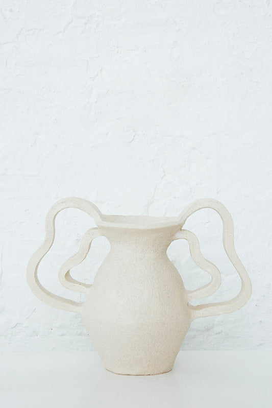 An Amphora Le Petit Doubles Vagues vase by Clandestine on a table next to a white wall.