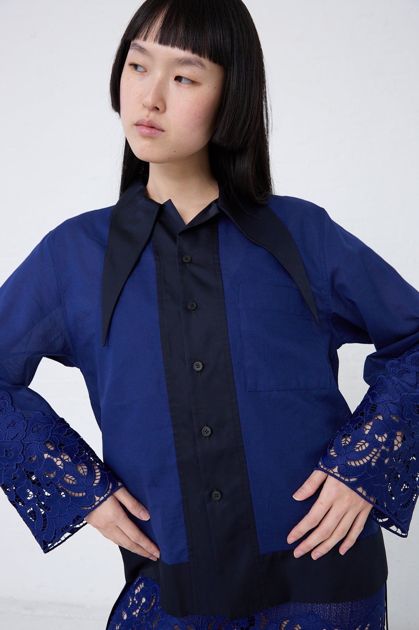 The model is wearing a TOGA PULLA Mesh Lace Shirt in Blue with lace sleeves.