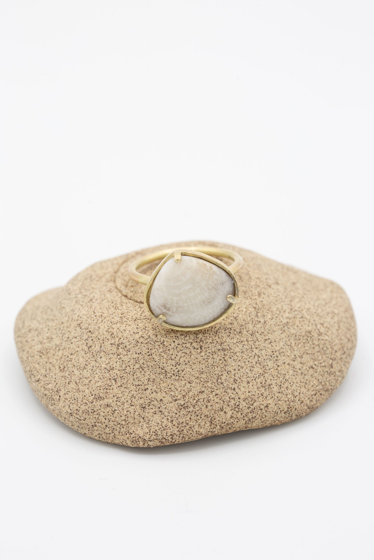 A La Ma r 14K Gold Ring 015 B with a white stone on top of a rock.